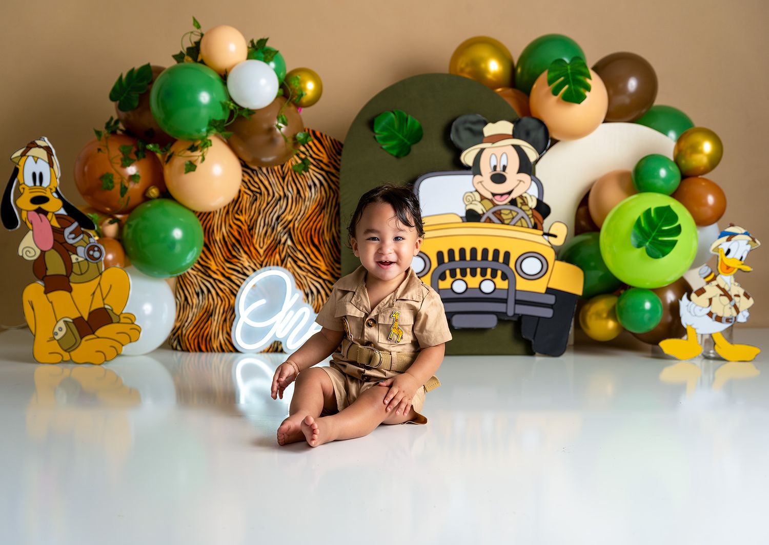 Jungle themed party backdrop with green balloons and safari decorations.
