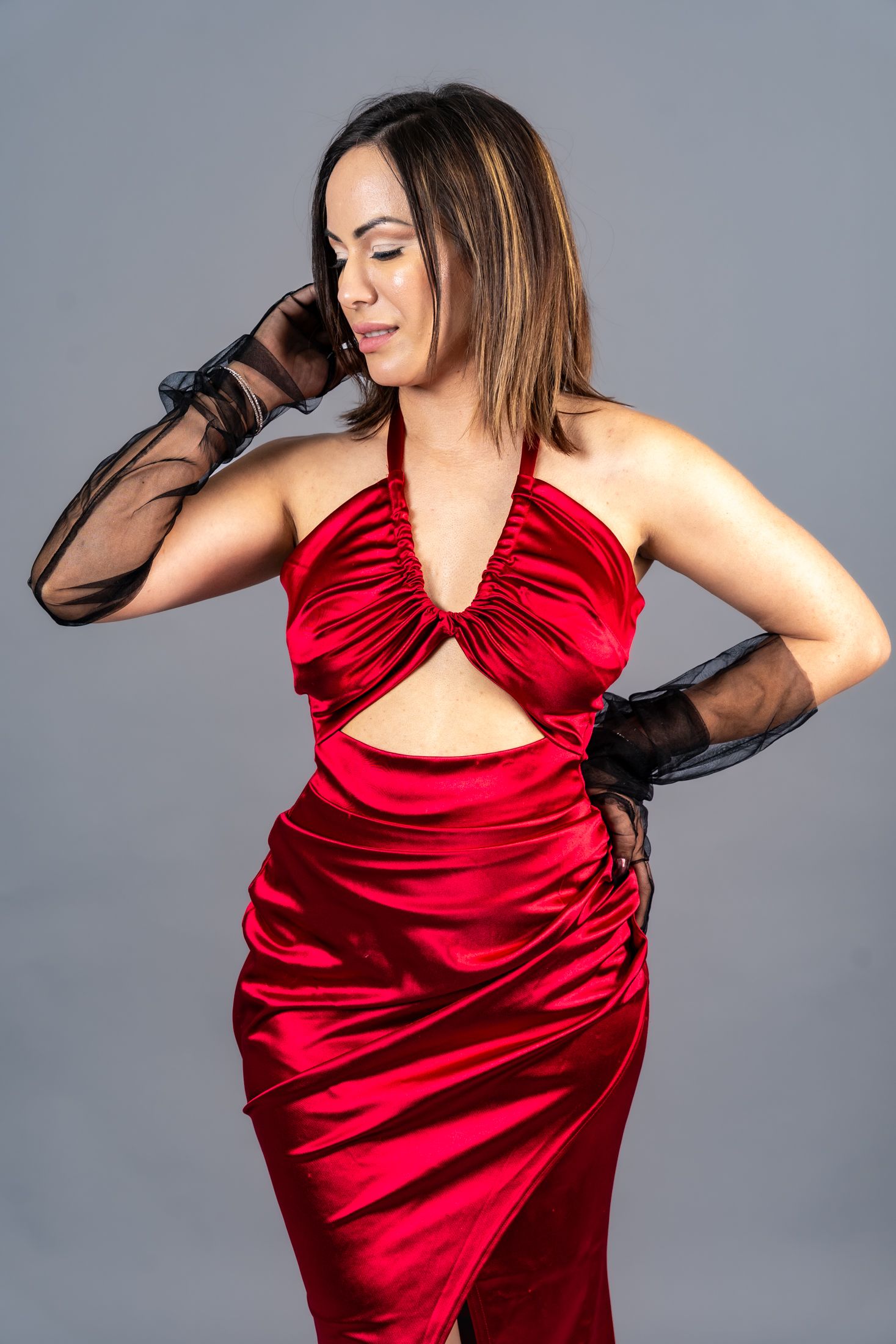 Model wearing flowing red dress strikes dramatic pose in studio setting.