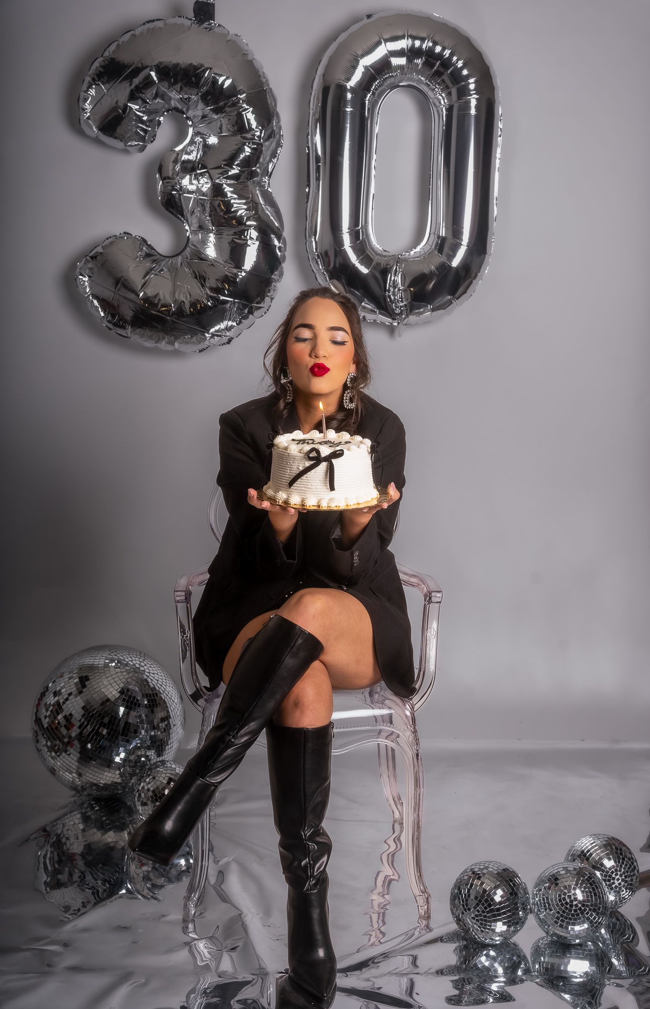 Birthday portrait with silver '30' balloons, black outfit, and celebration cake.