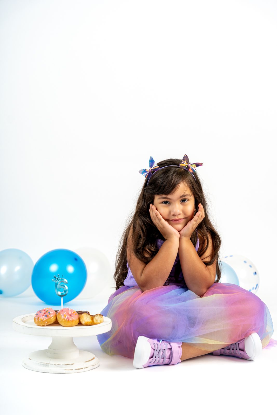 Whimsical birthday portrait with blue balloons and purple tulle dress.