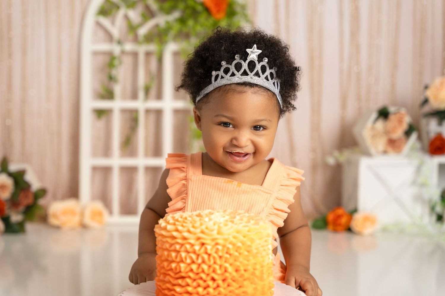 Birthday celebration setup with orange cake and floral decorations in studio setting.