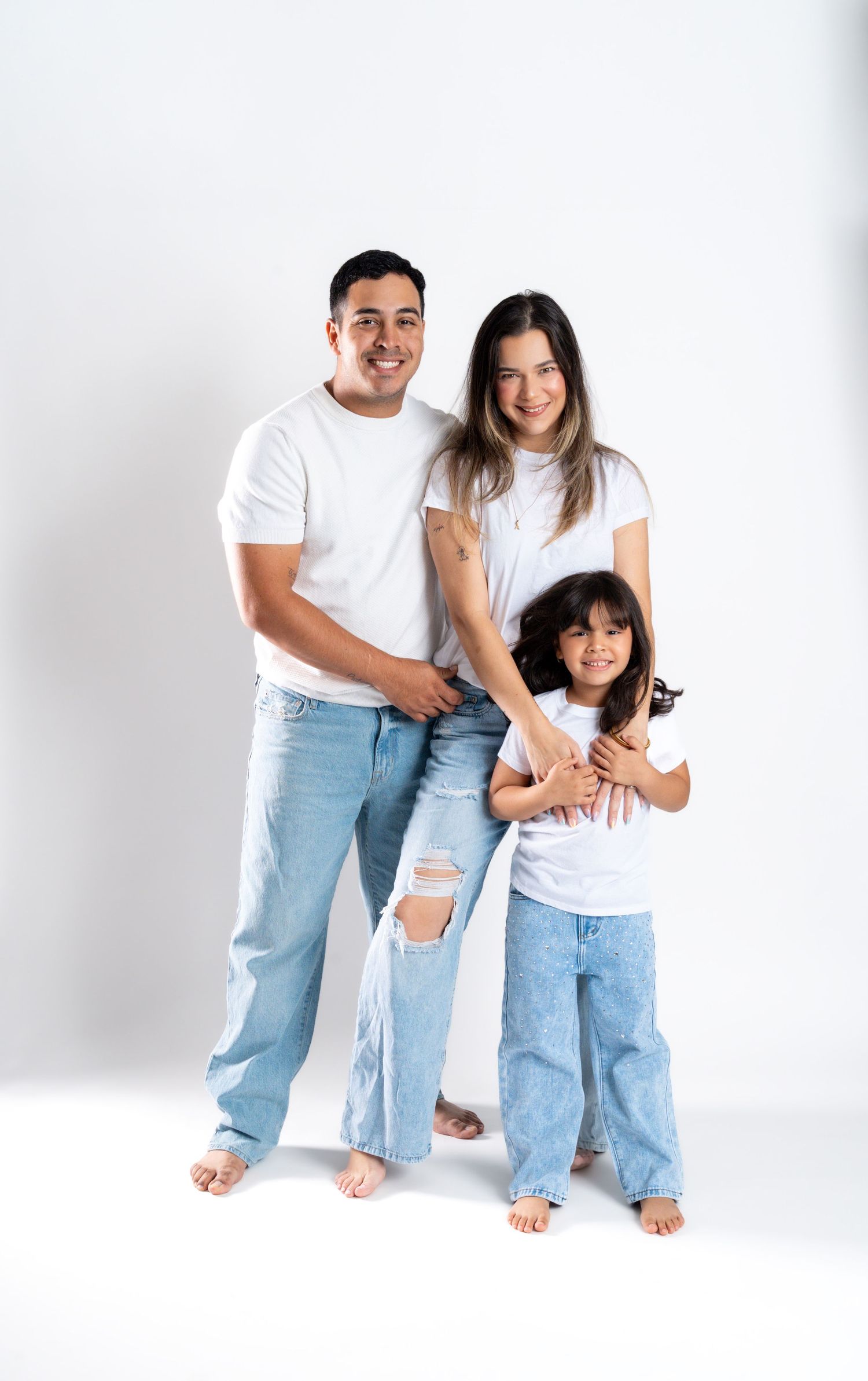 Casual family portrait with coordinated denim and white t-shirt outfits.