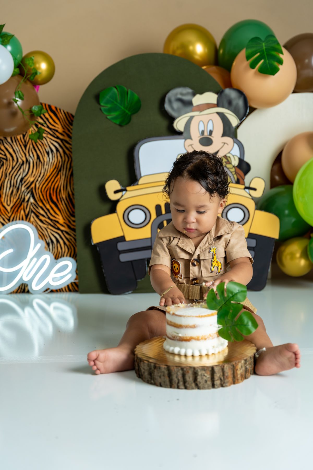 Safari themed cake smash setup with tiger prints and Mickey Mouse decorations.