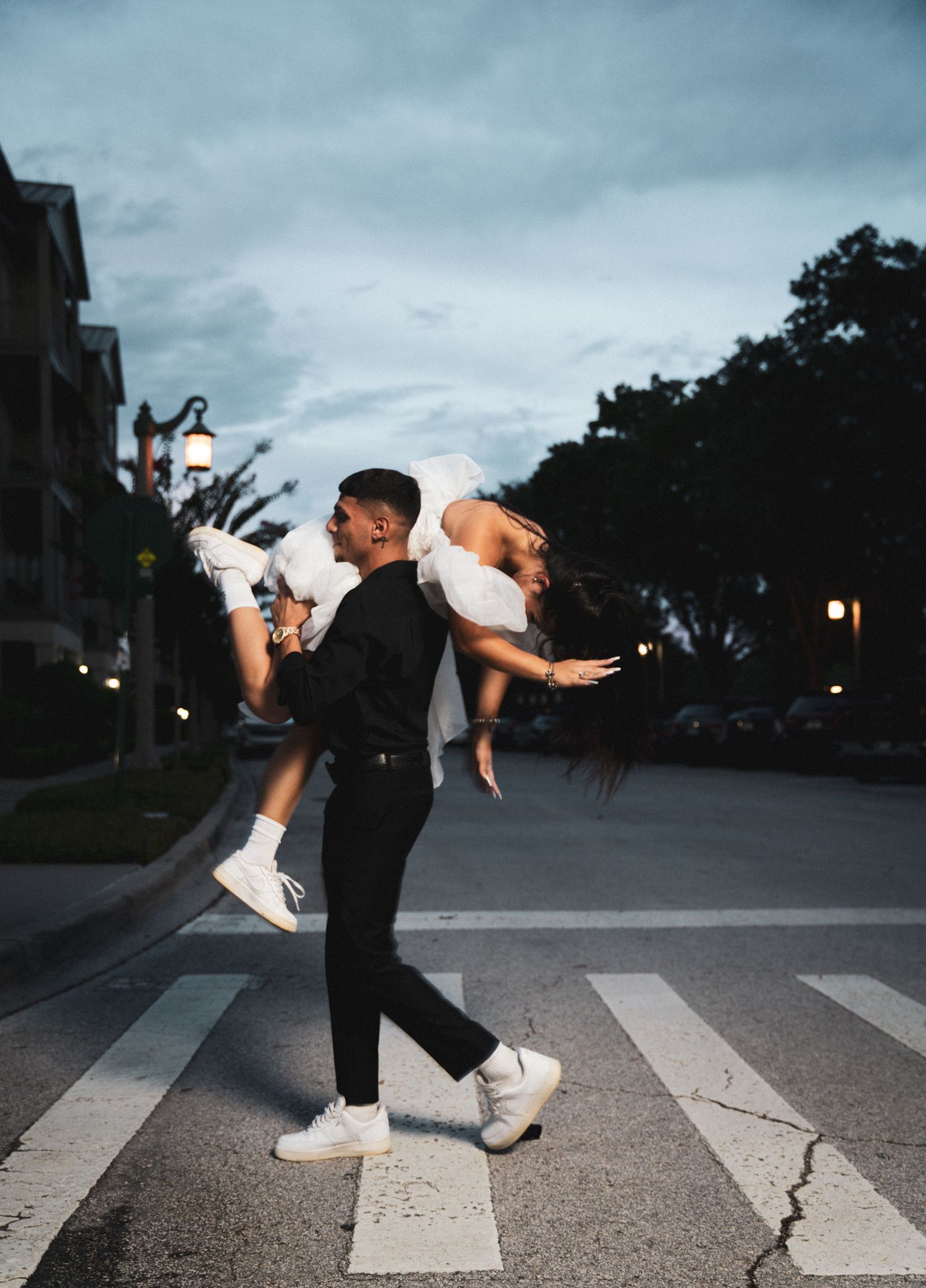 Dramatic dance dip poses on crosswalk at dusk in urban setting.