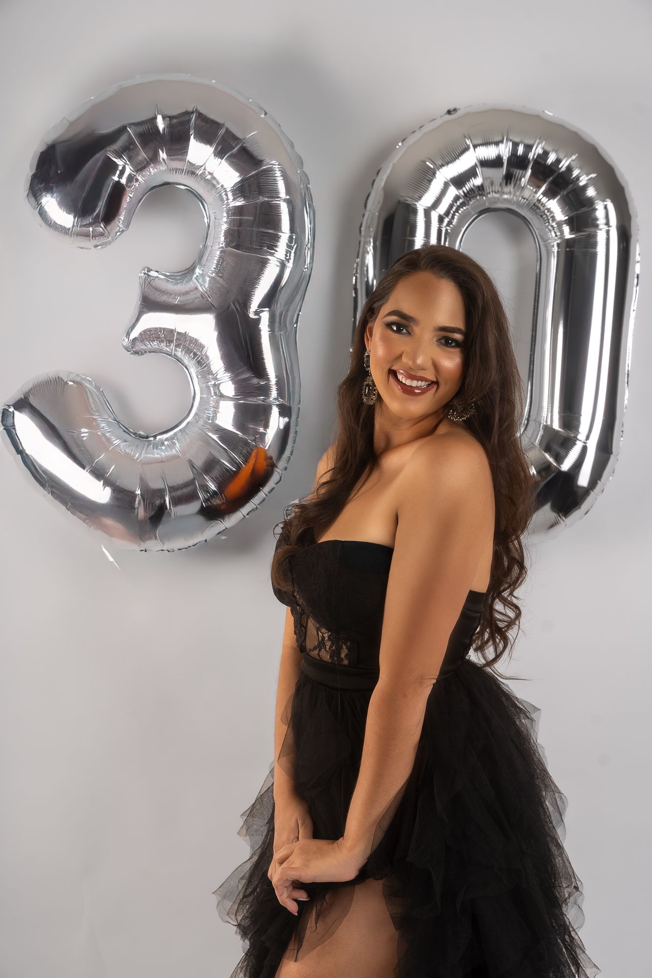 Festive photoshoot with silver number balloons and black tulle dress.