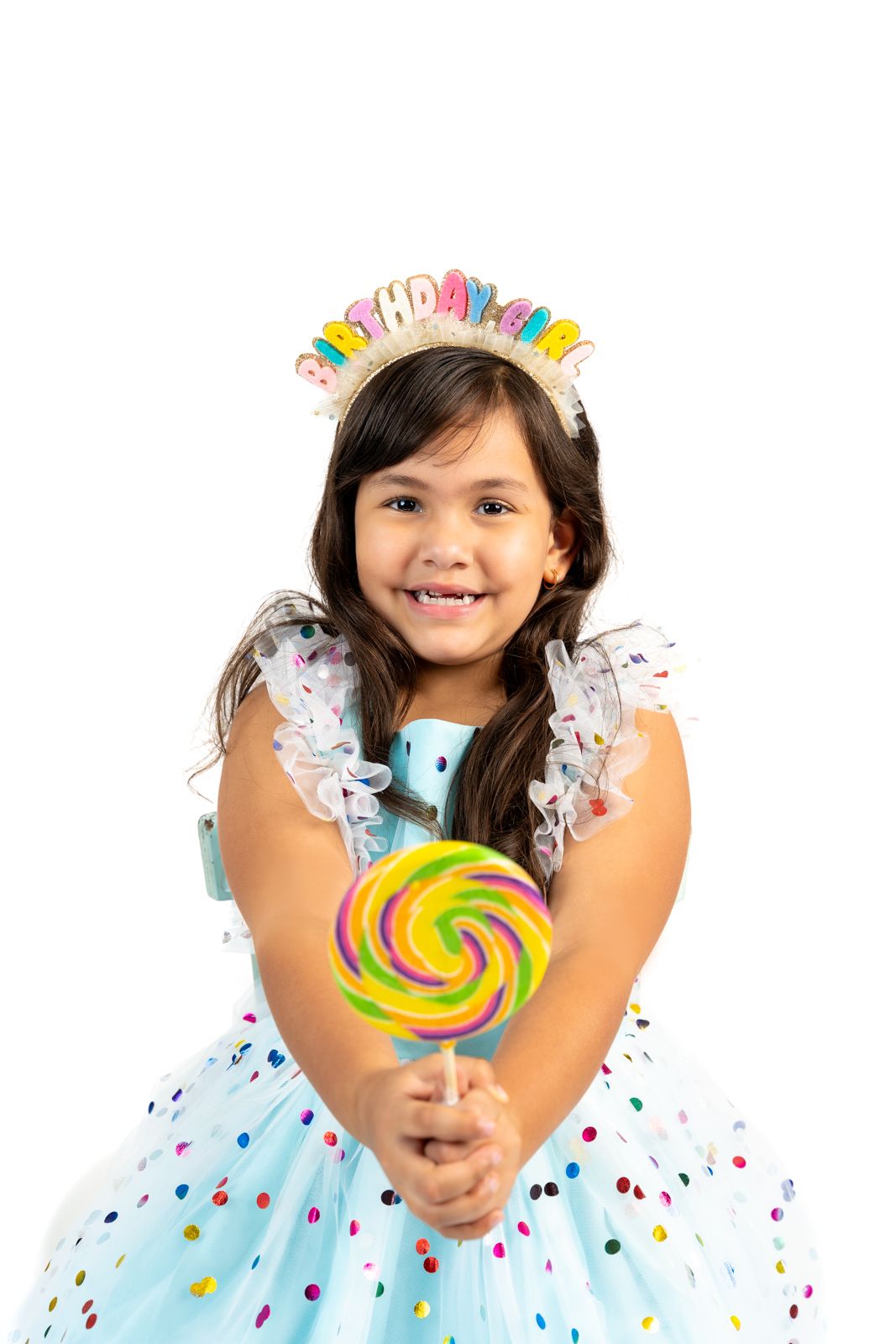 Birthday celebration with rainbow lollipop and confetti against white background.