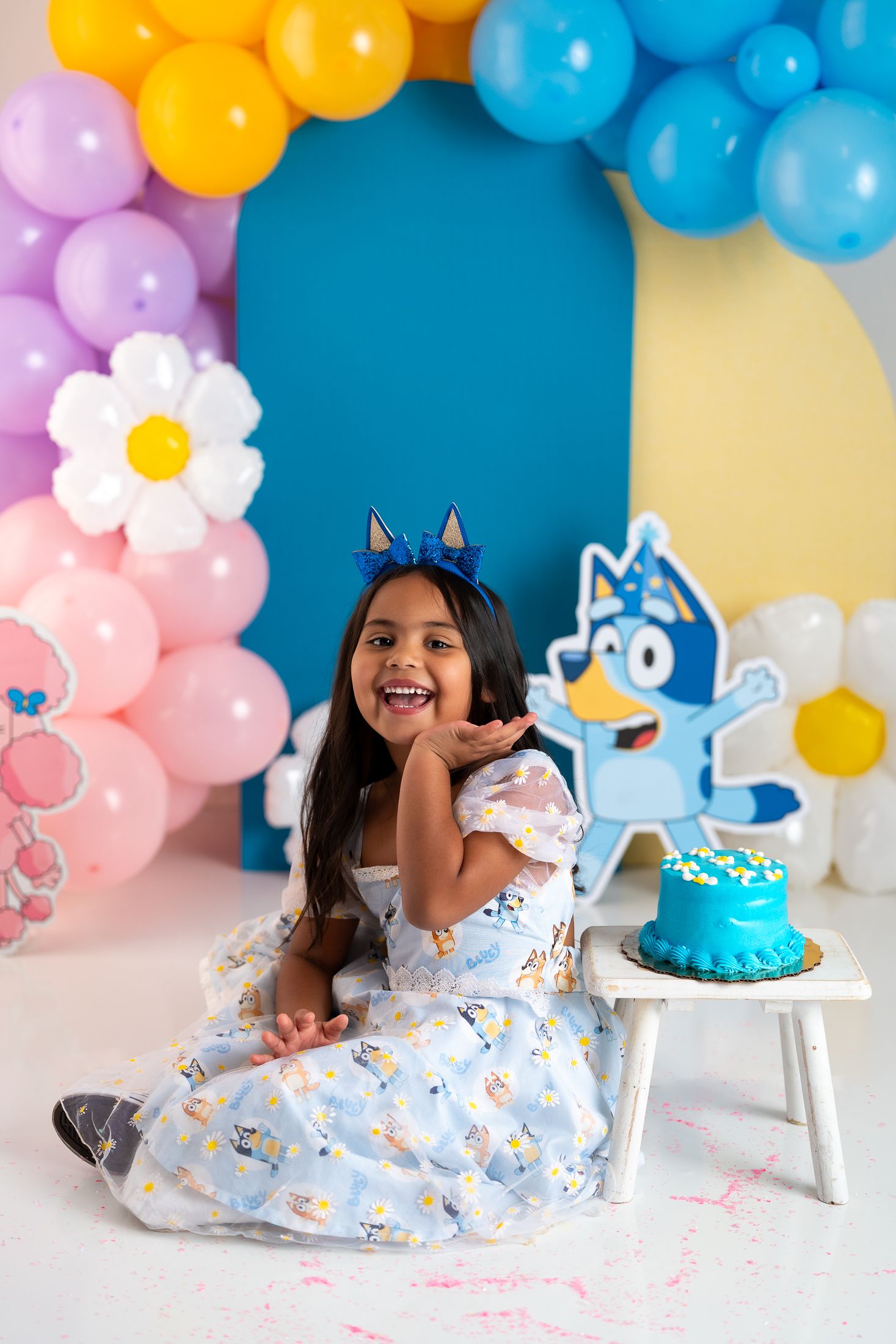 Joyful celebration scene with balloon garland and decorative cake setup.