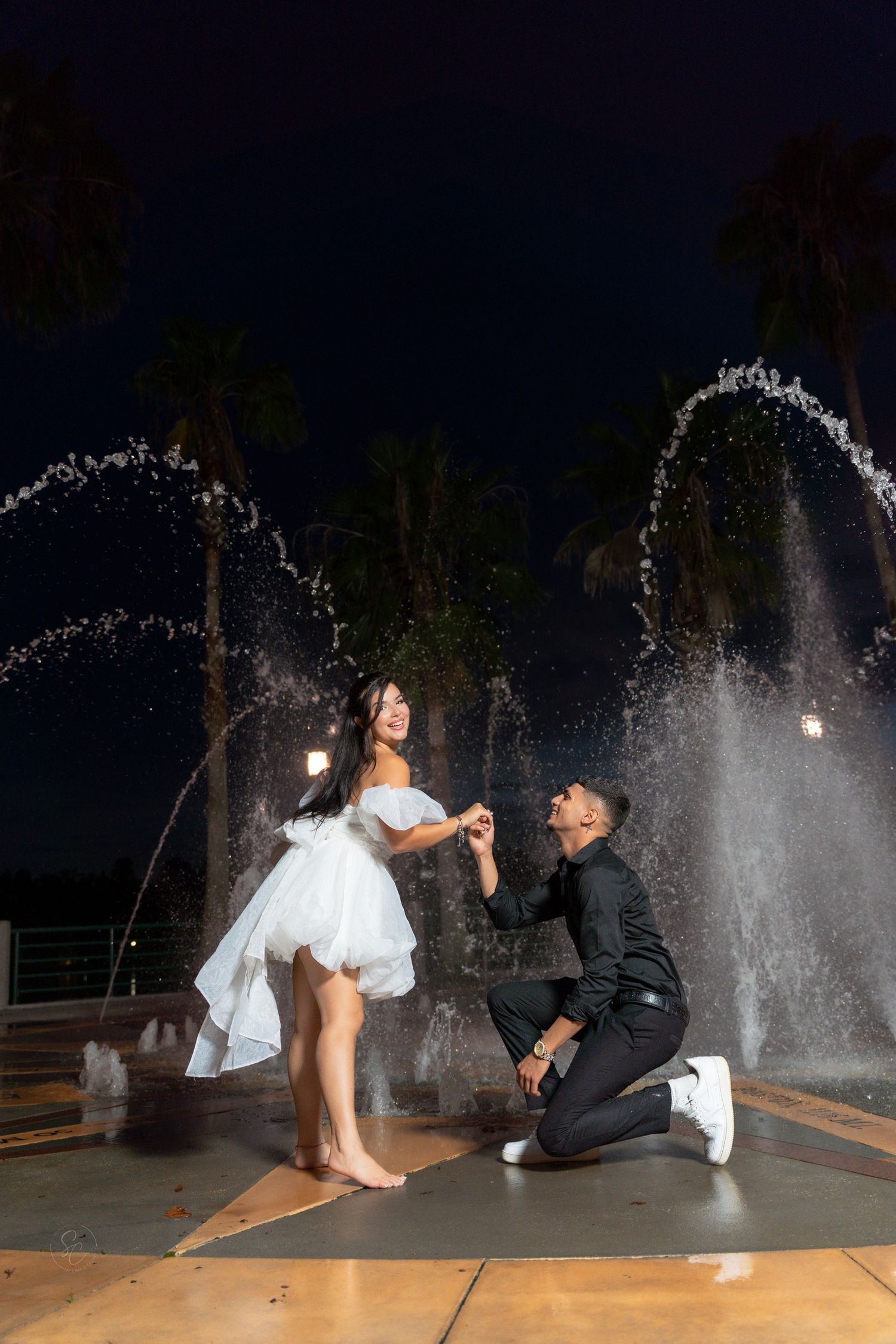 A romantic proposal scene with water fountains creating a magical backdrop.