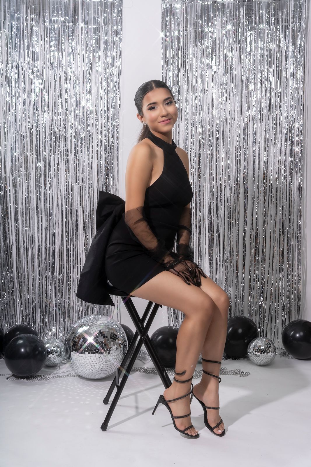Studio photoshoot with black outfit against silver tinsel backdrop.