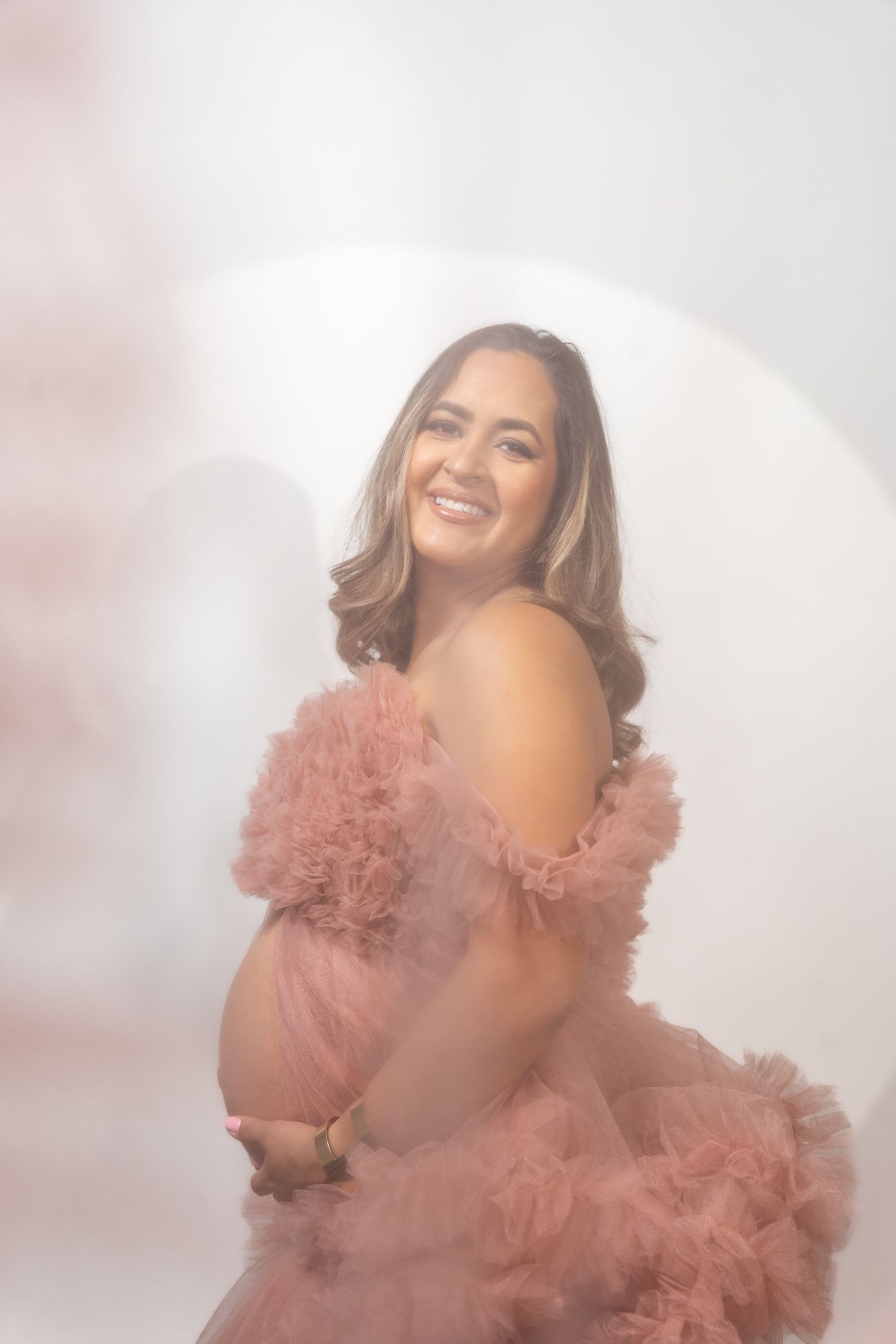 A dreamy portrait featuring a pink tulle dress against a soft white background.