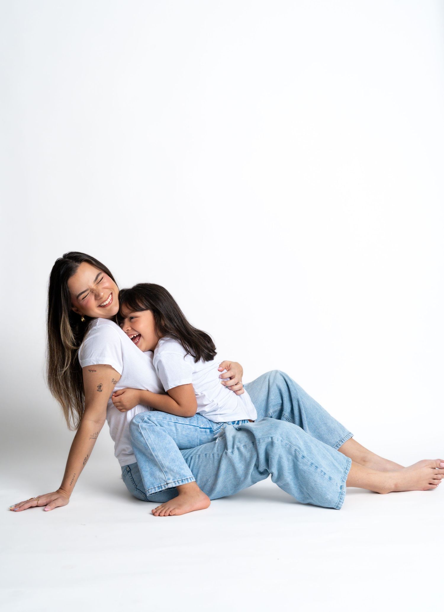 Relaxed poses on white background wearing matching jeans and white shirts.