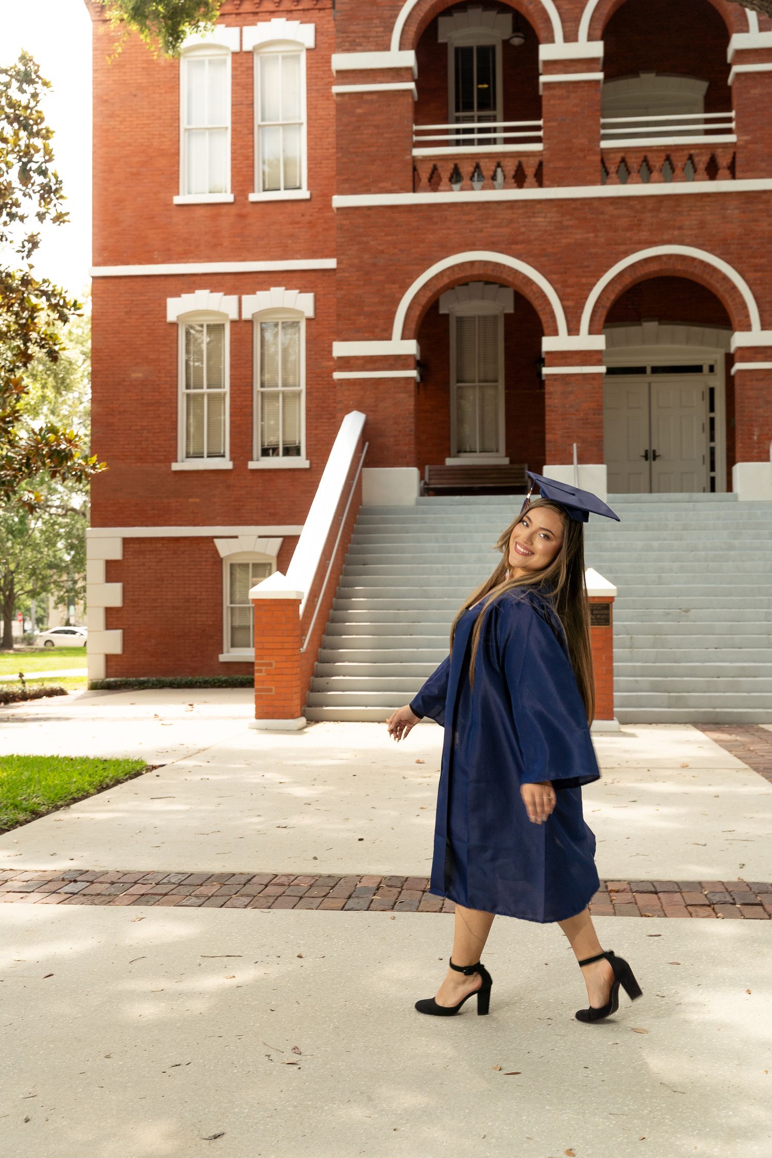 A graduate in blue cap and gown poses in front of a brick building in a series of celebratory graduation photos.