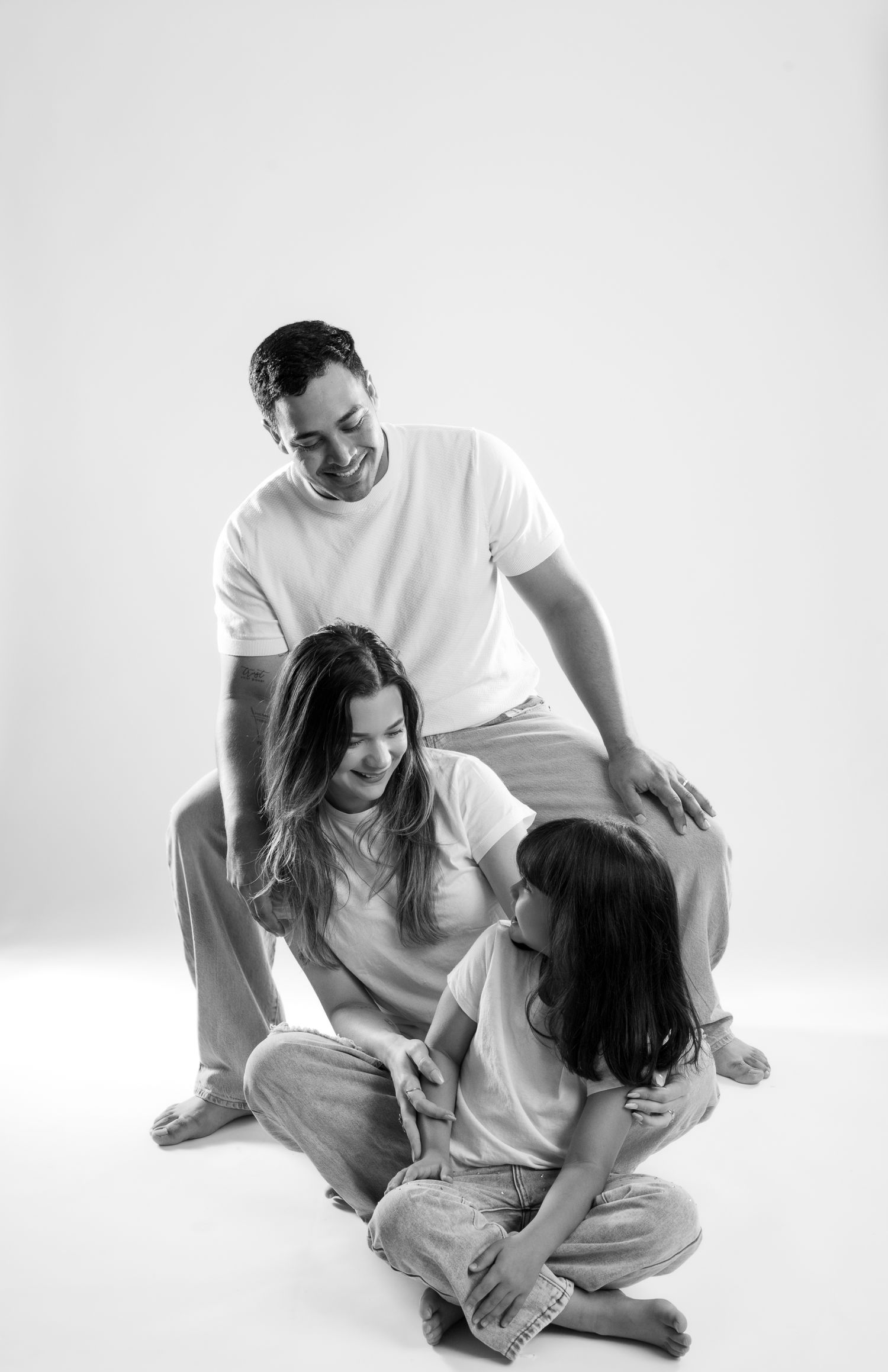 Candid family moments captured in black and white against white studio backdrop.