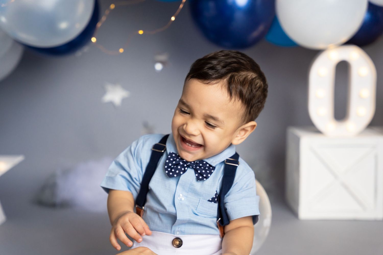 Cake smash photo session with navy and light blue theme featuring festive balloon decorations.