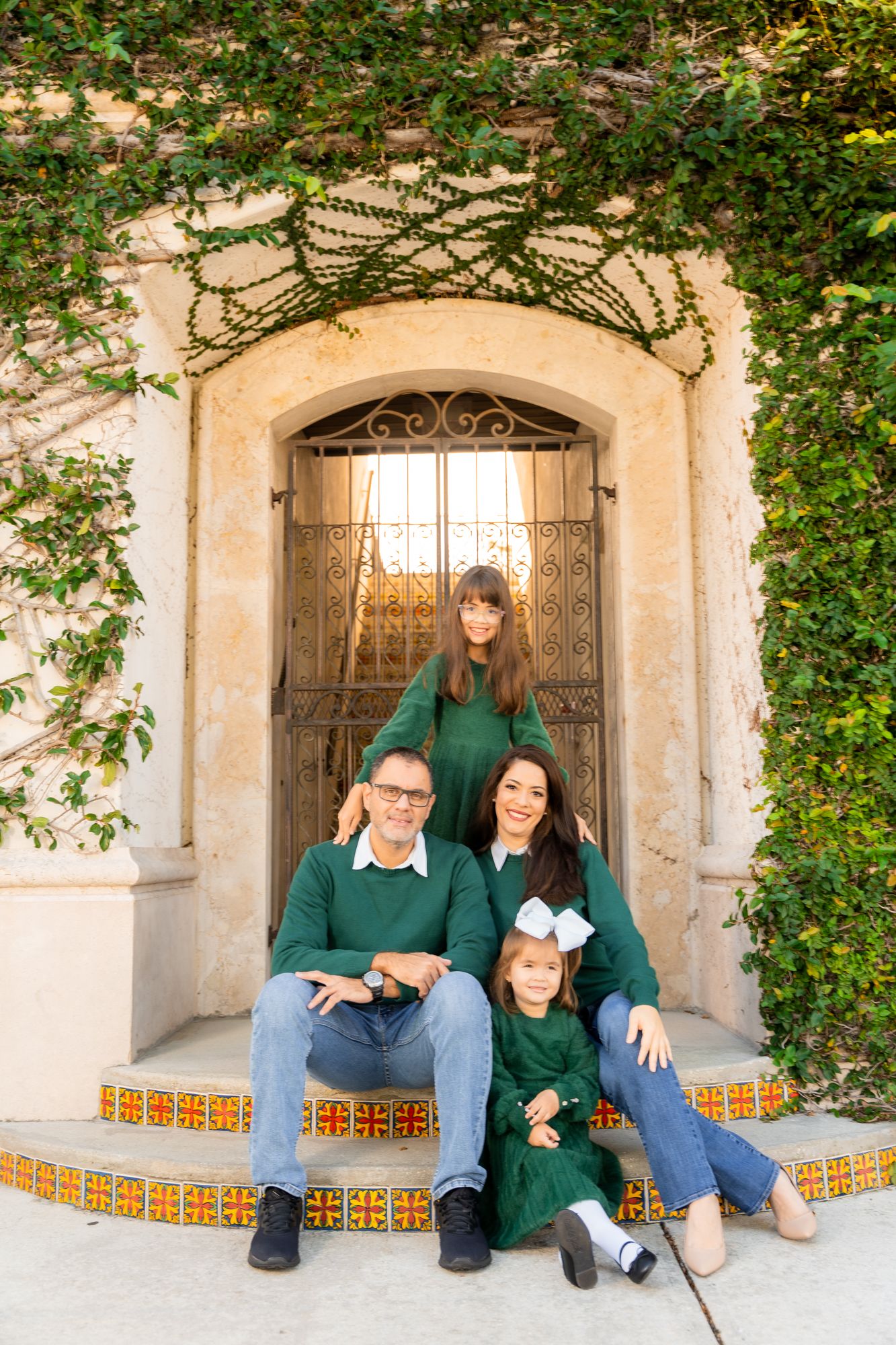 Family portrait session in an archway with decorative tiles and climbing vines.
