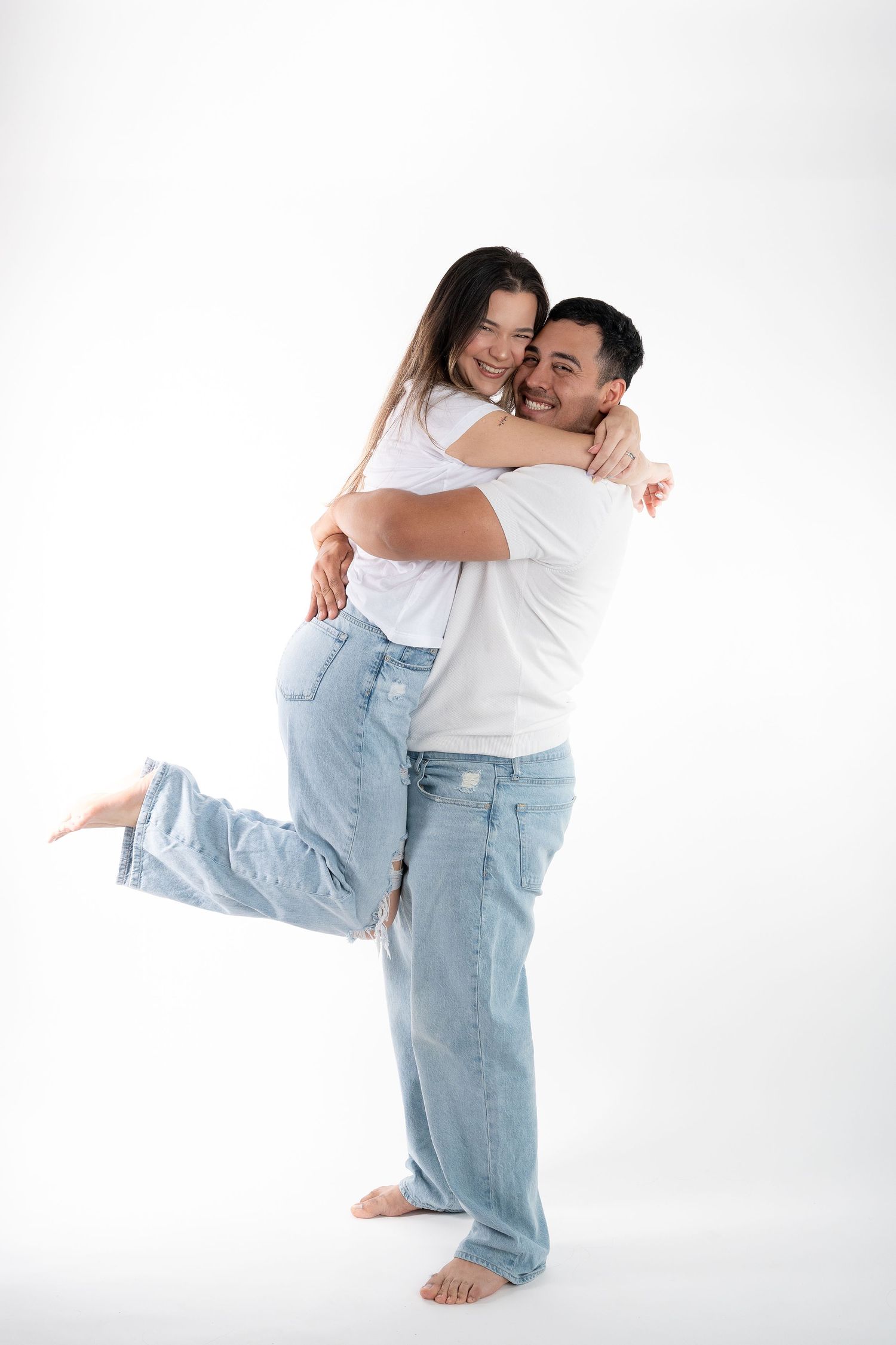 A joyful couple hugging and laughing together while wearing matching casual outfits.