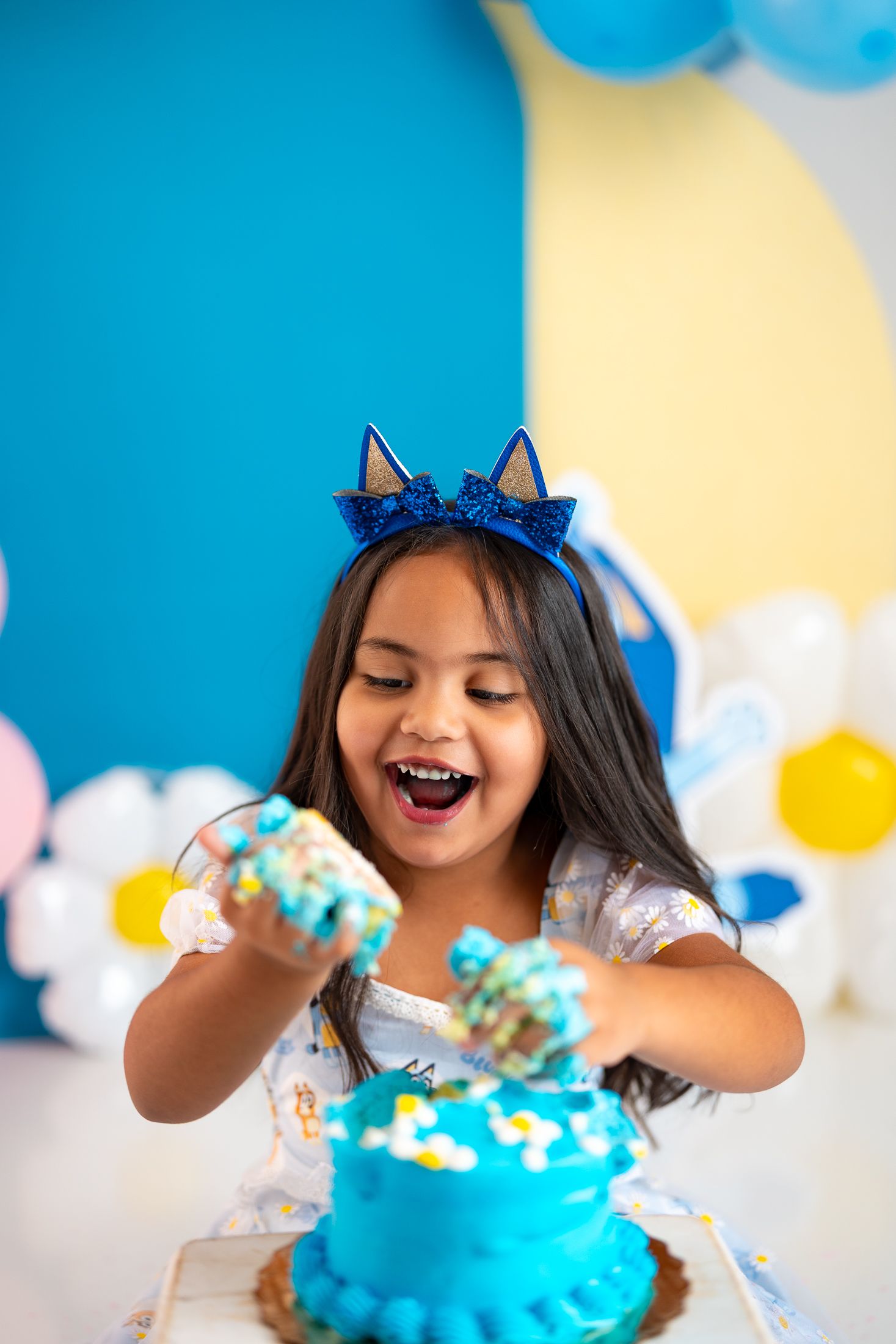 Playful cake smash photo session with blue frosted cake and festive decorations.