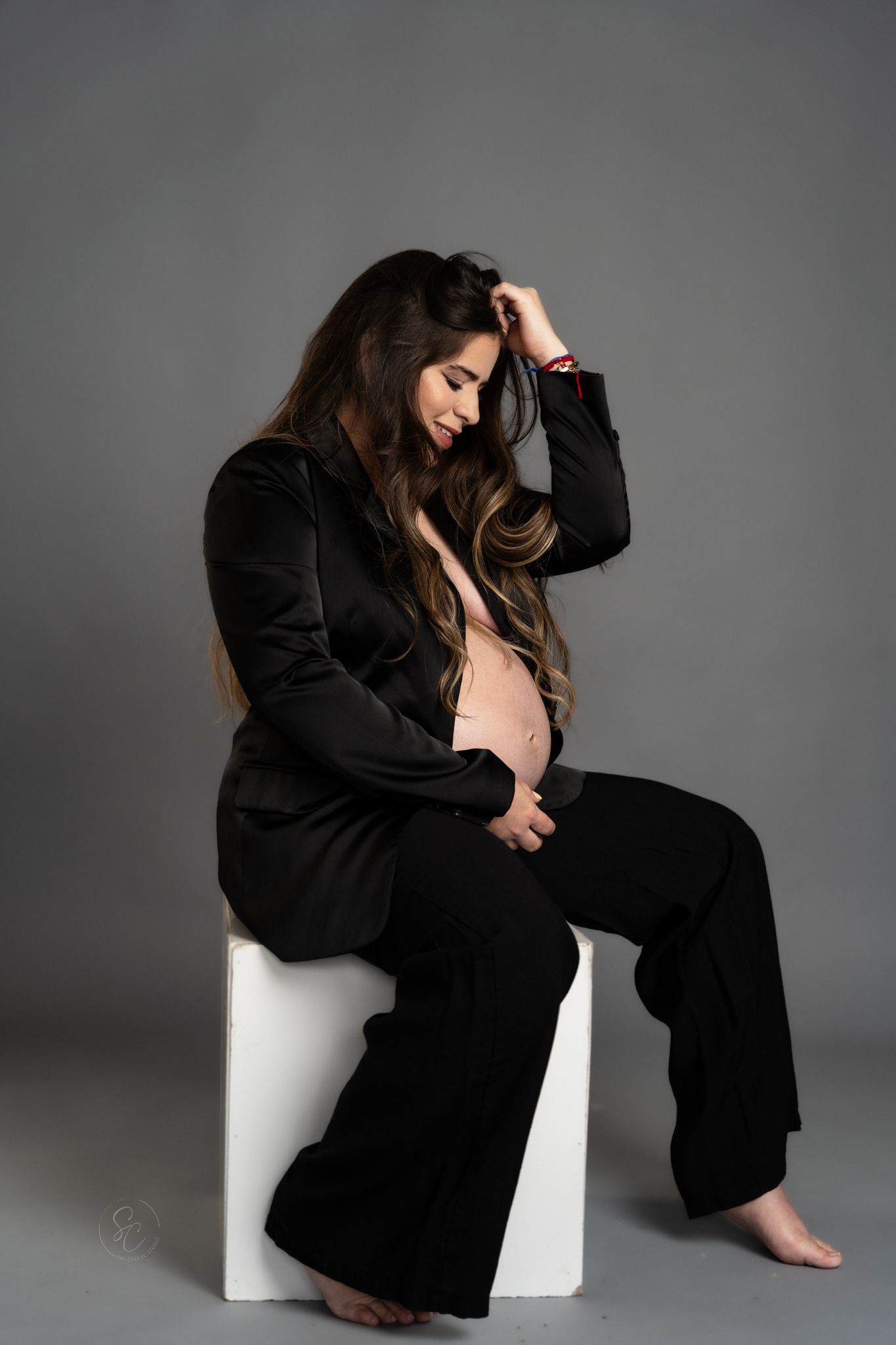Dramatic black and white maternity photos showing contemplative poses in dark attire.