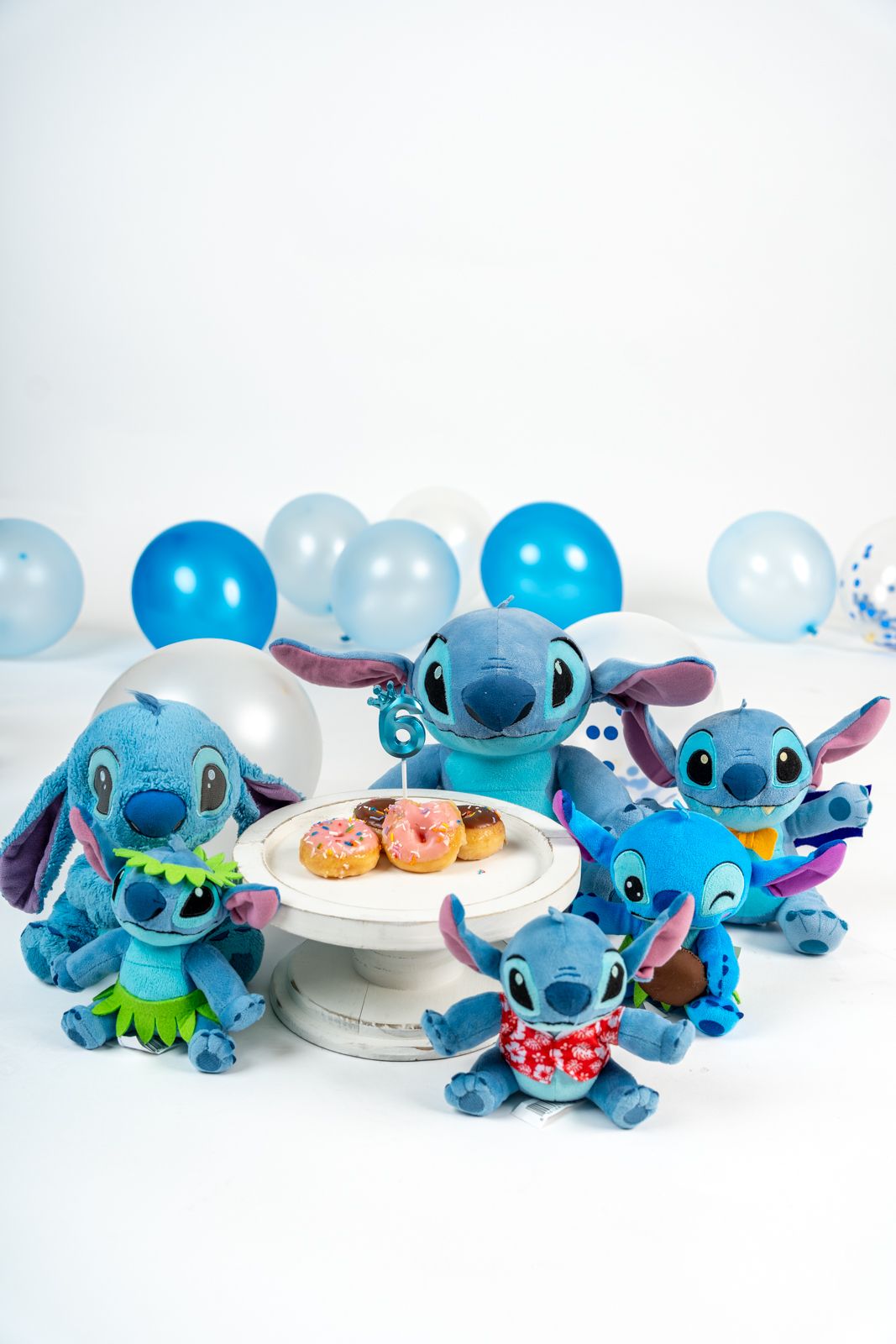Collection of blue Stitch plush toys from Disney's Lilo & Stitch arranged in a row with various poses.