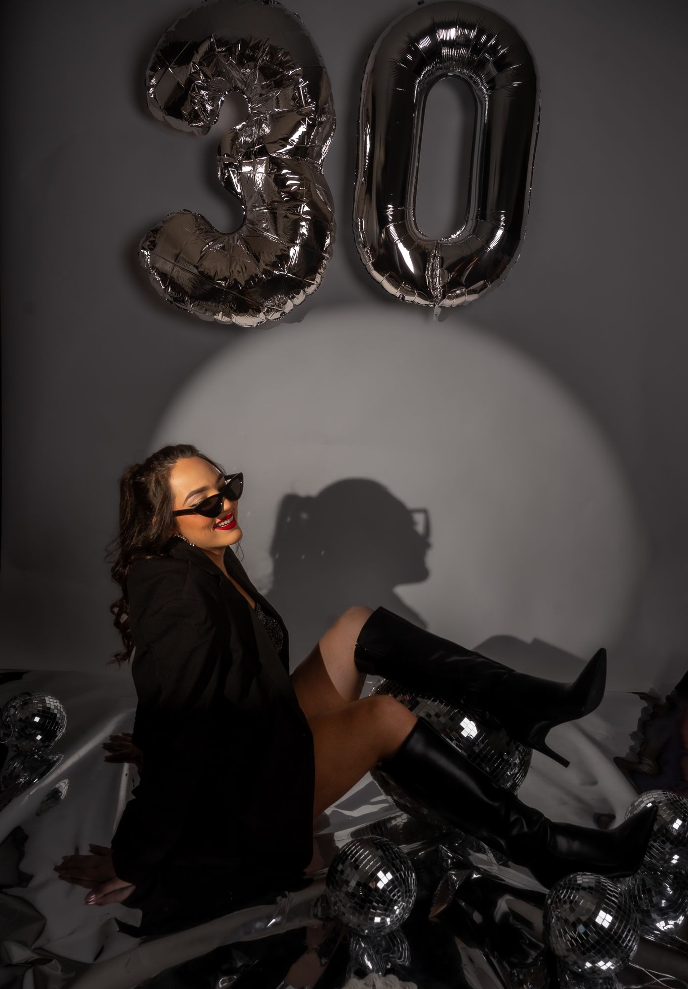 Studio portrait with black blazer and disco balls in dramatic lighting.