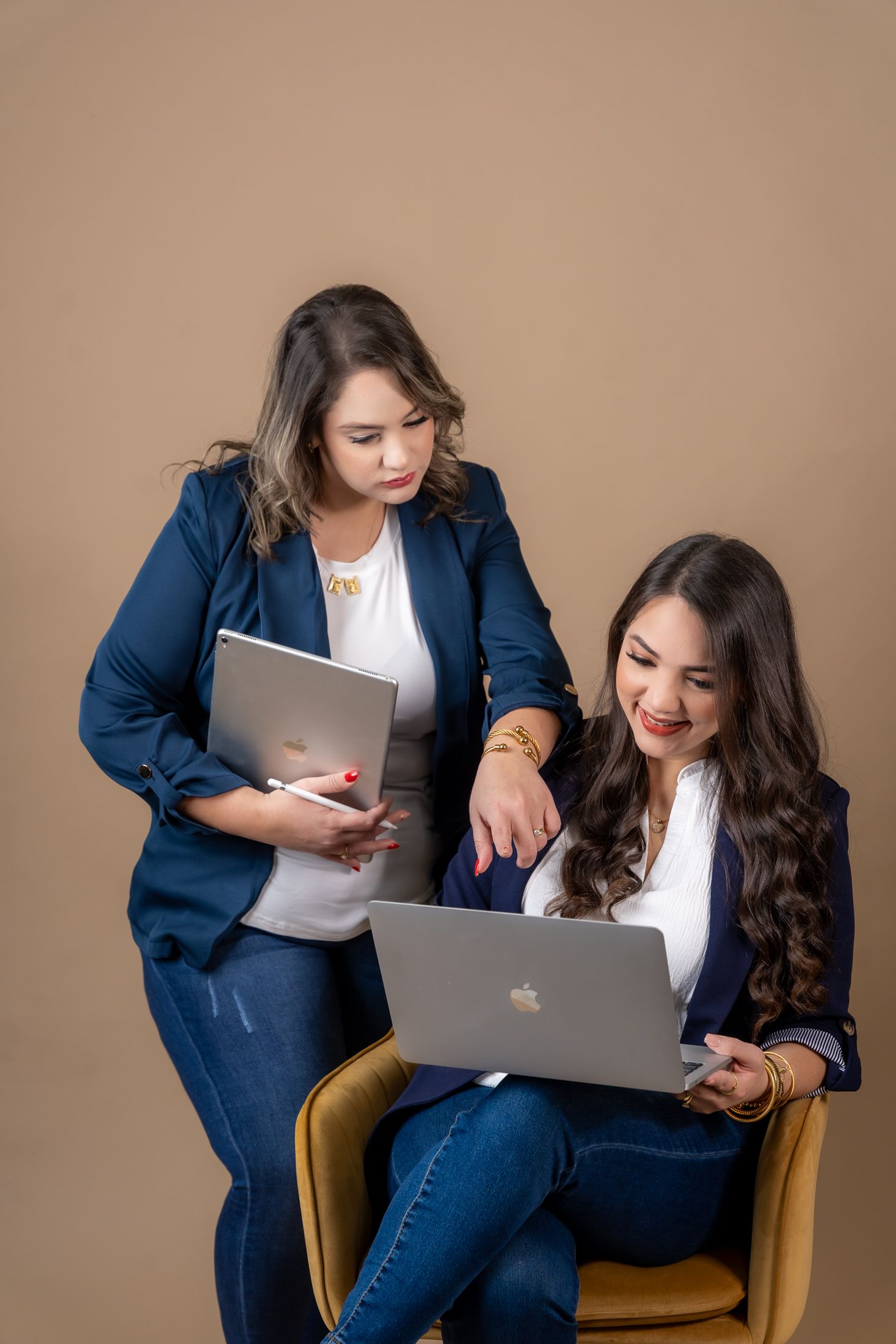 Two professionals reviewing work on laptops while seated in modern office setting.