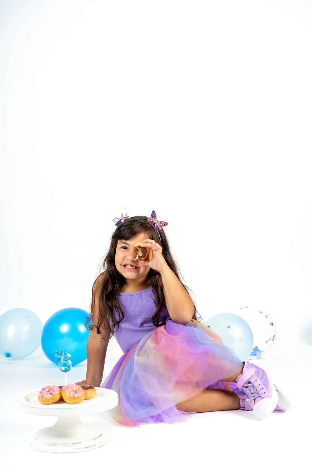 Birthday photo session with blue balloons and purple tulle outfit.