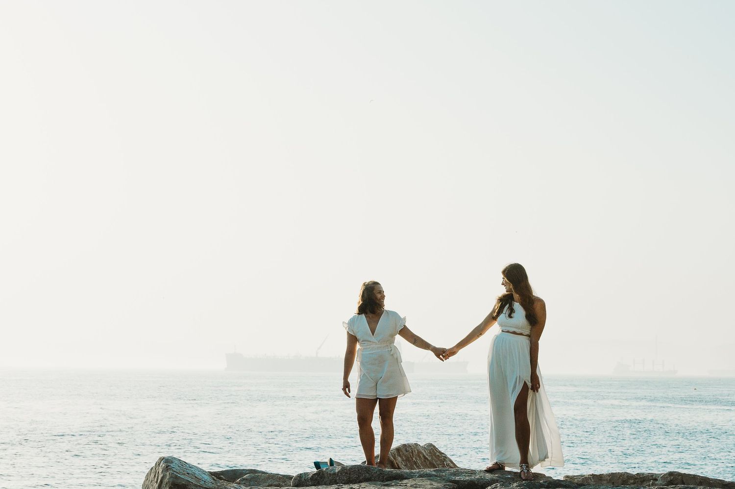 two brides looking at each other by the sea