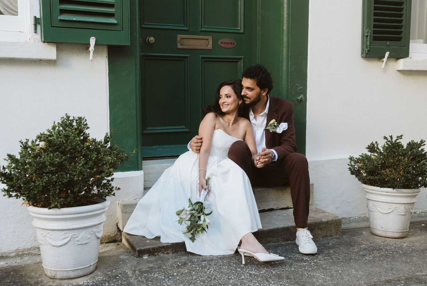 bride and groom sitting in a green door in town area