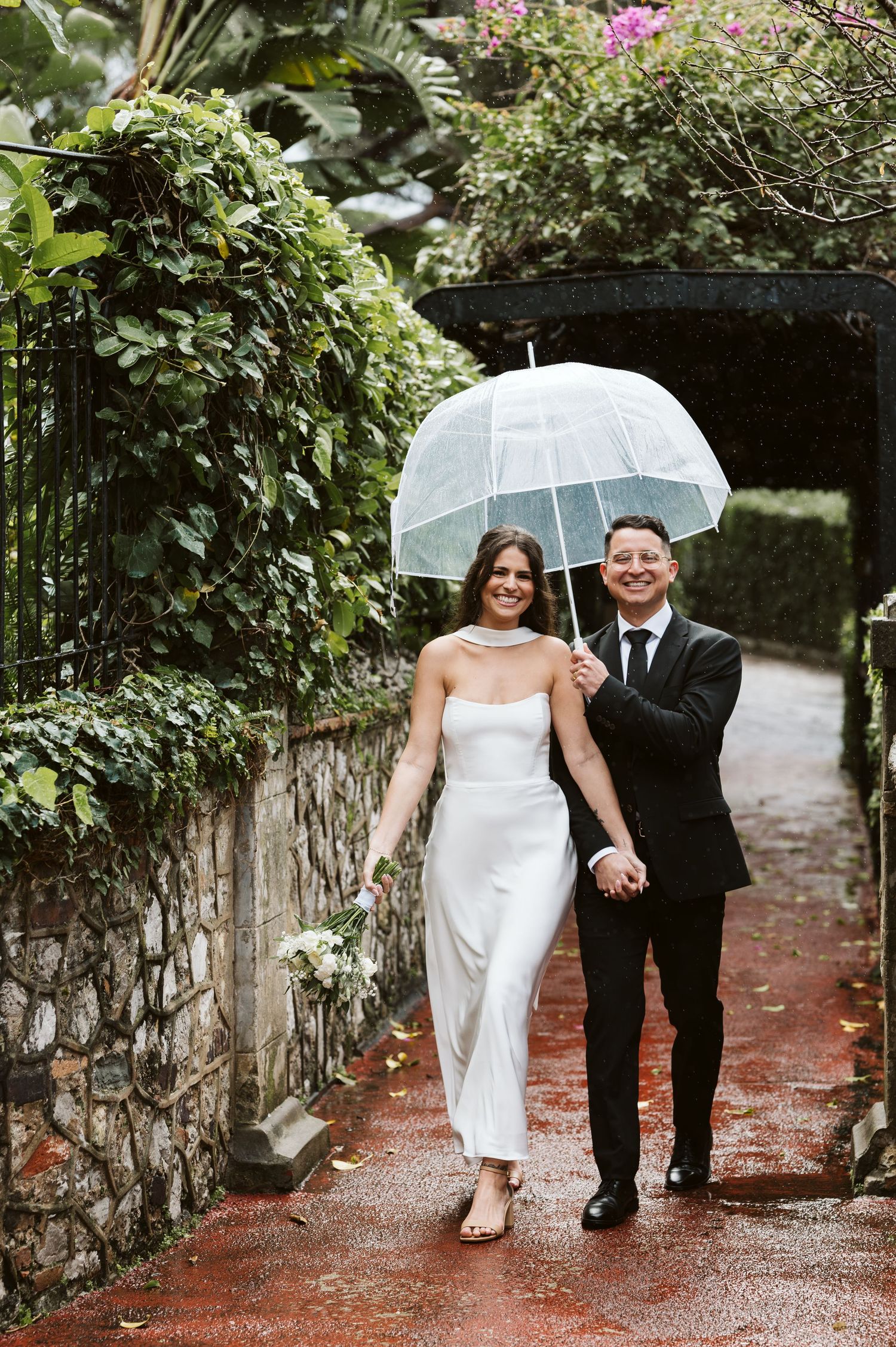 bride and groom walking in alameda Gardens smiling despite the rain