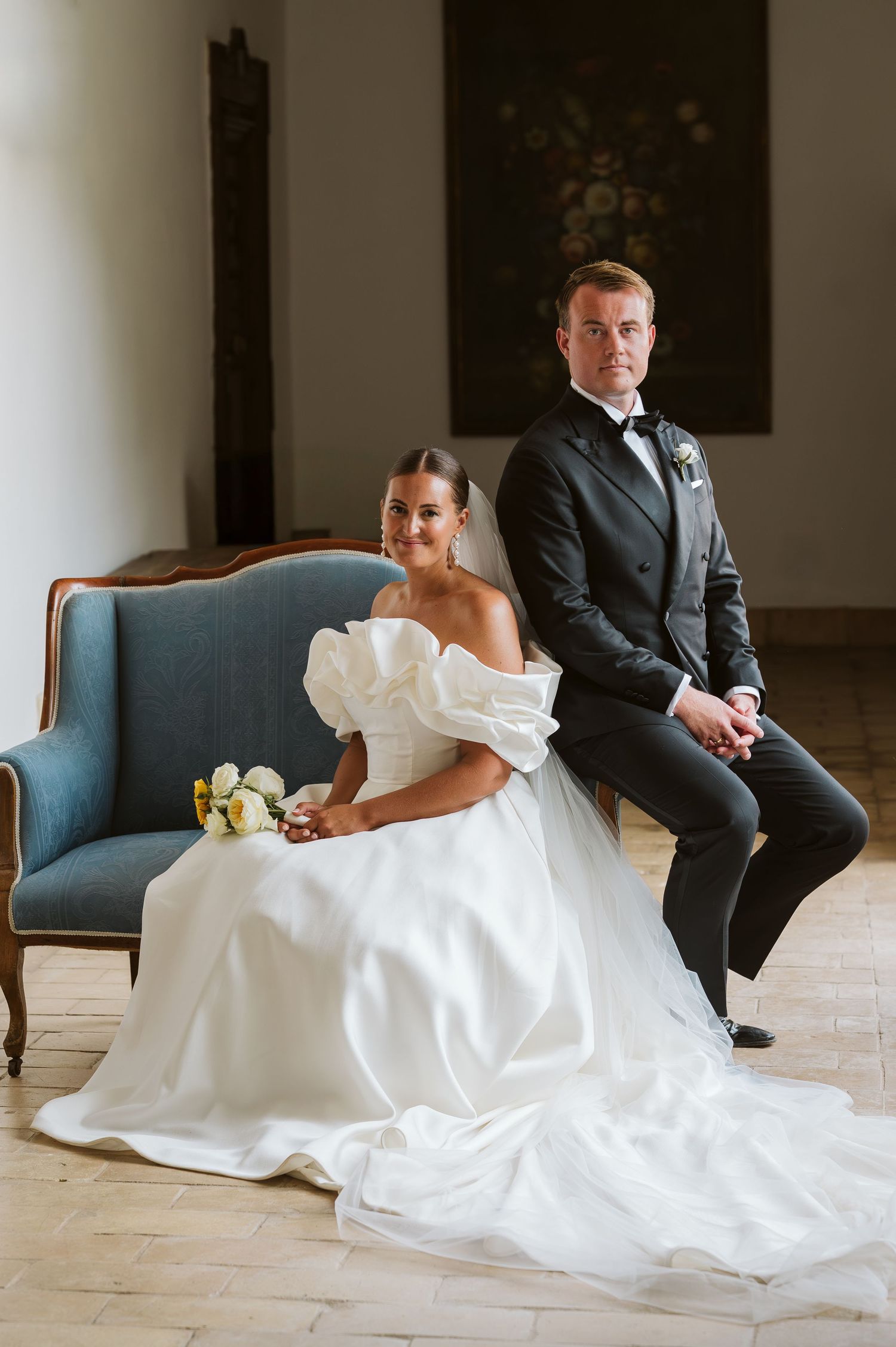 bride sitting on a sofa and groom posing for a classic photo at Finca monasterio