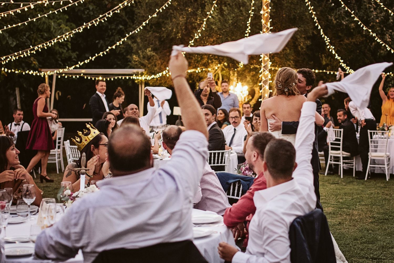 bride and groom kissing and the guests waving scarfs