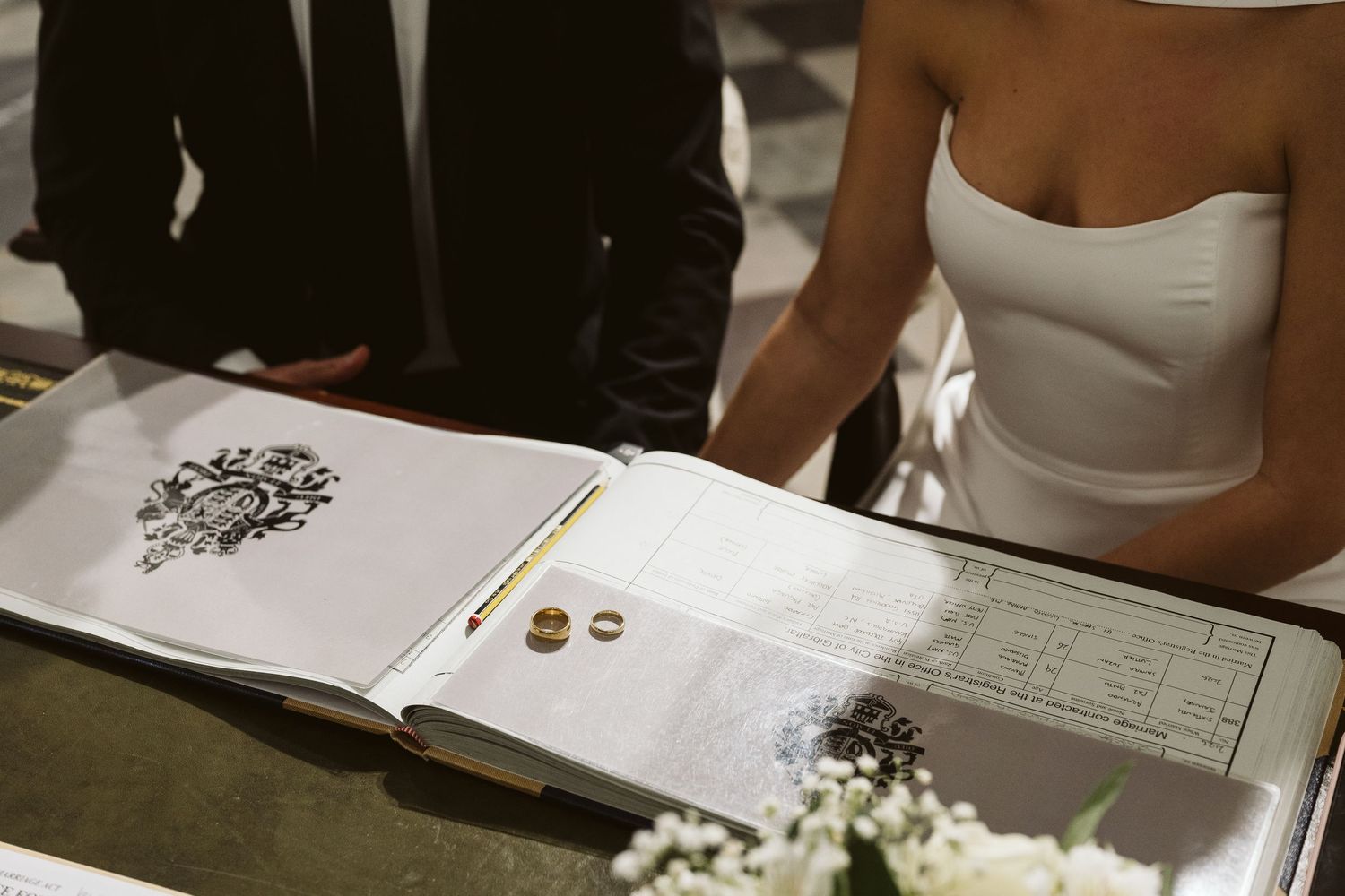 Tight shot of just the bride and grooms torso with focus on the rings at the ceremony