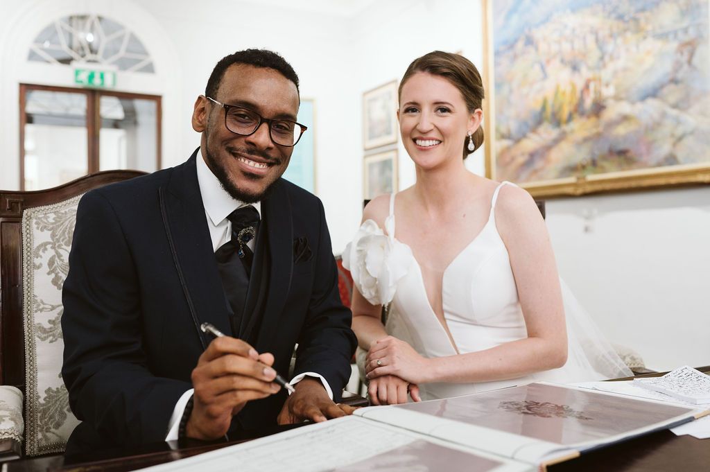 bride and groom posing for a photo when signing the book