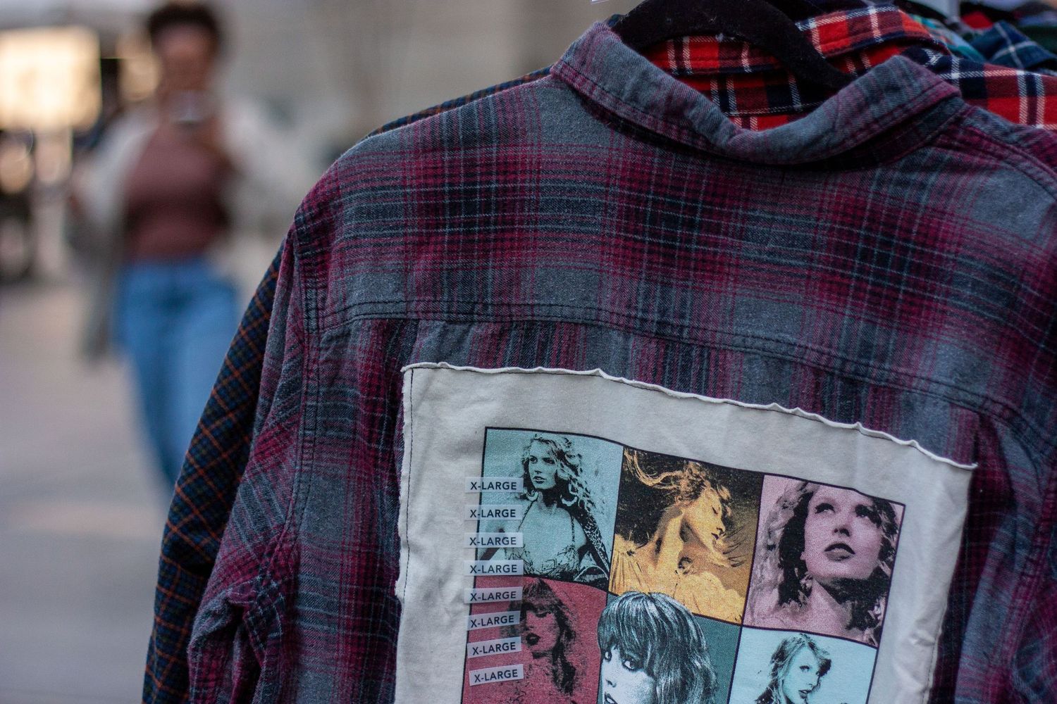 Plaid flannel jacket with Taylor Swift Eras Tour graphic patch on the back displayed outdoors.