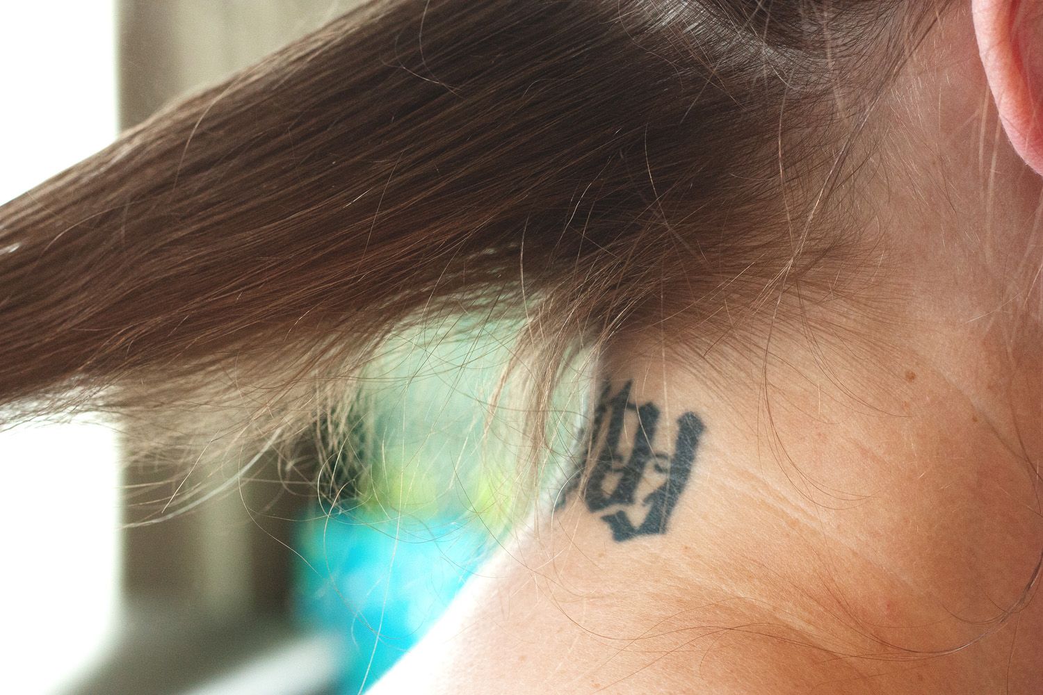 Detail of brown hair being curled with a styling tool against a light background.