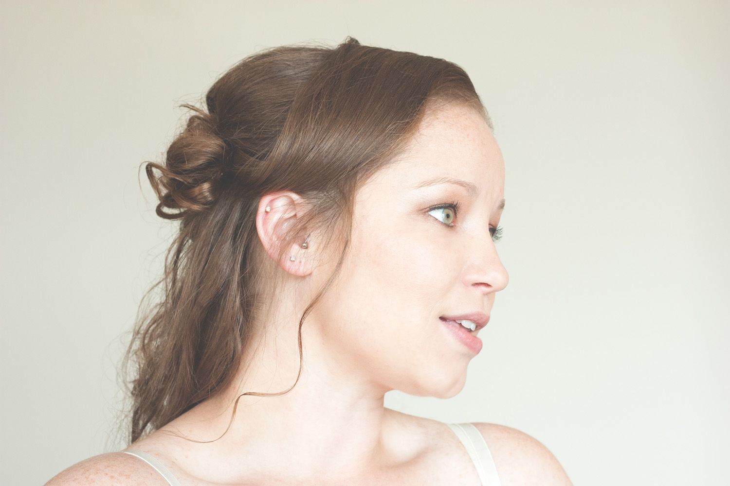 Side profile view of an elegant hairstyle with soft curls against a white wall.
