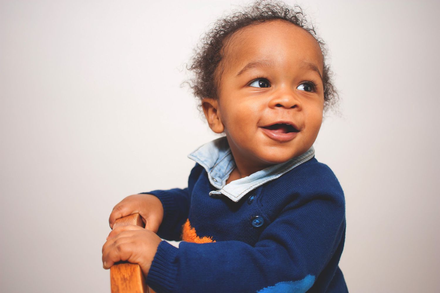 Child wearing navy blue outfit smiling against white background.