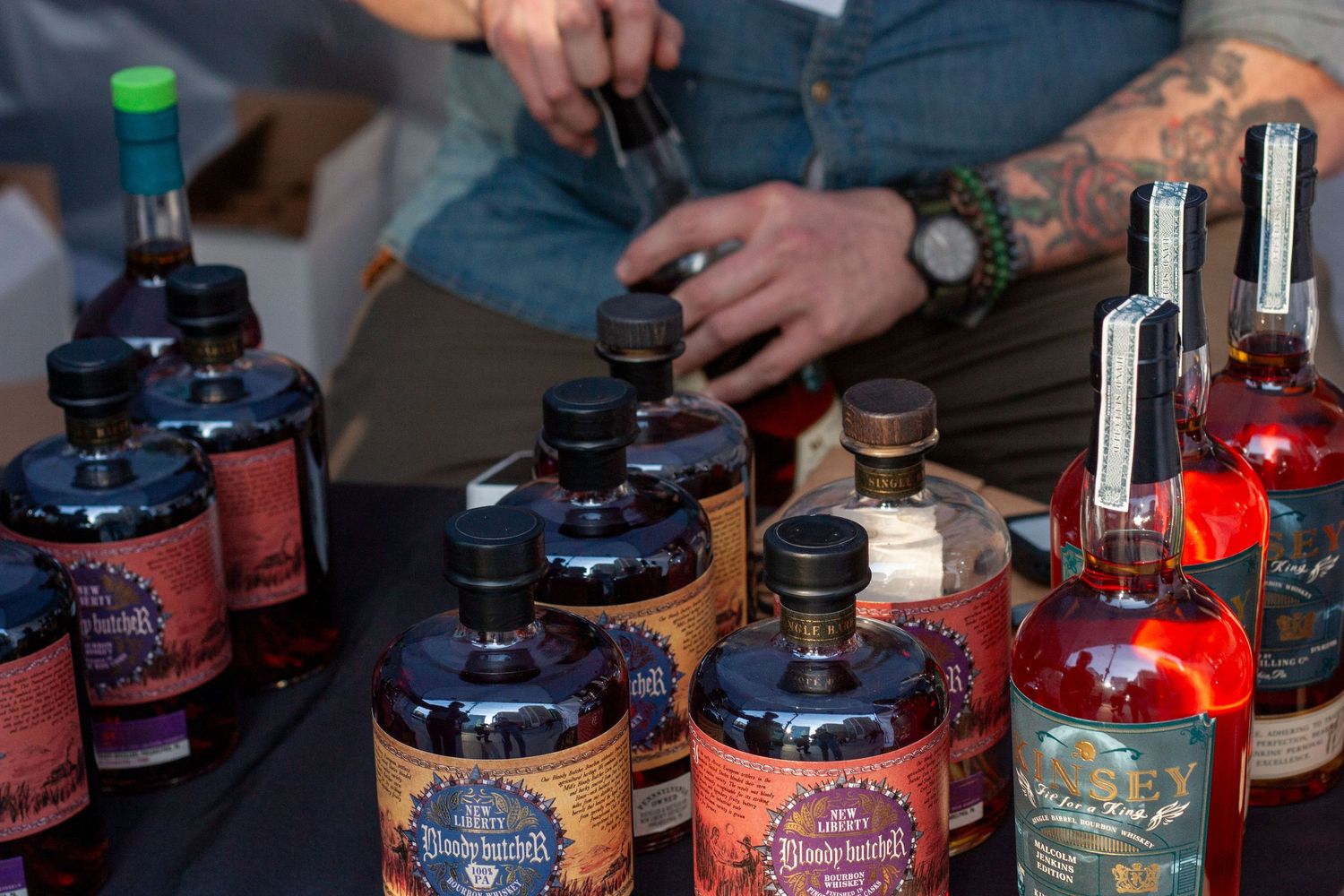 Assorted craft bourbon and whiskey bottles displayed on a table at a spirits tasting event.
