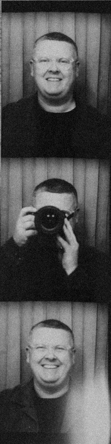 Black and white photo booth strip showing a smiling man with glasses holding a camera in the middle frame.