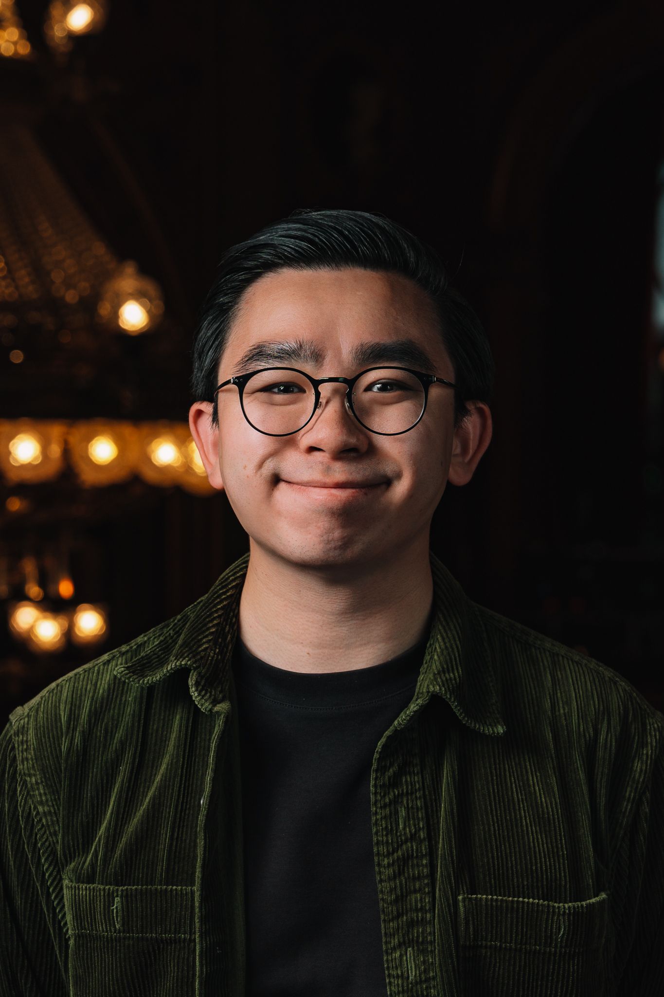 Portrait series against dark background with warm lighting and green corduroy jacket.