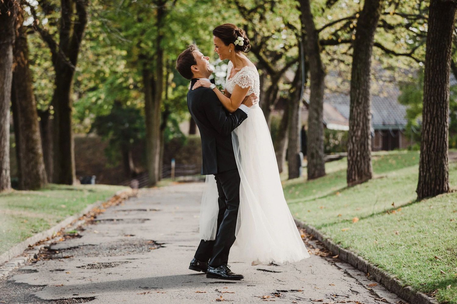 Wedding couple poses in a scenic wooded area with tall trees.