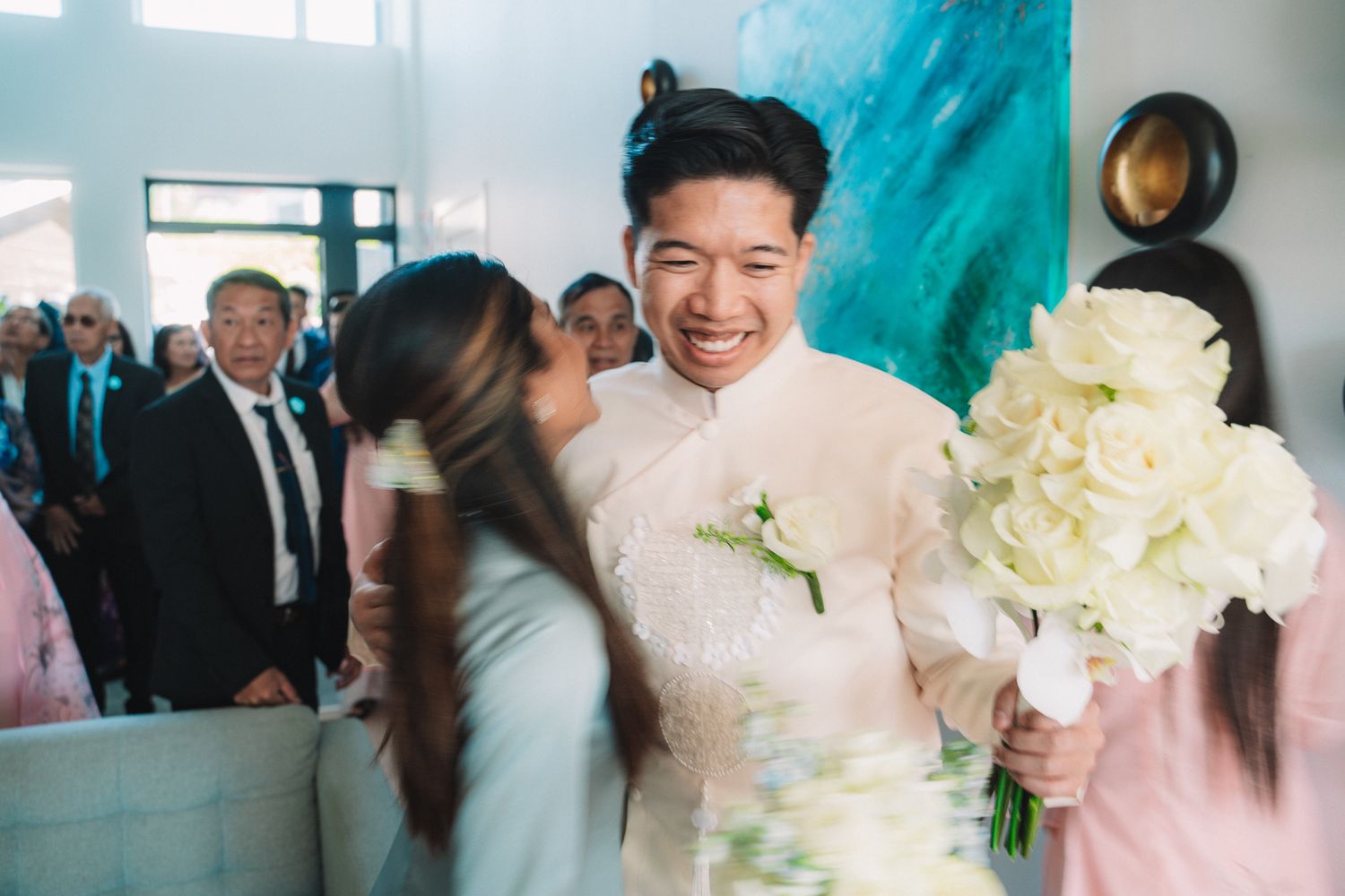 Wedding party members in formal attire gathering around white floral bouquets.