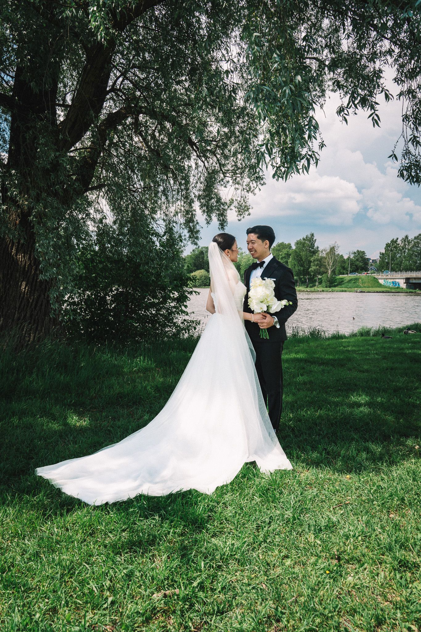Bride and groom share intimate moments in outdoor setting with flowing white dress.