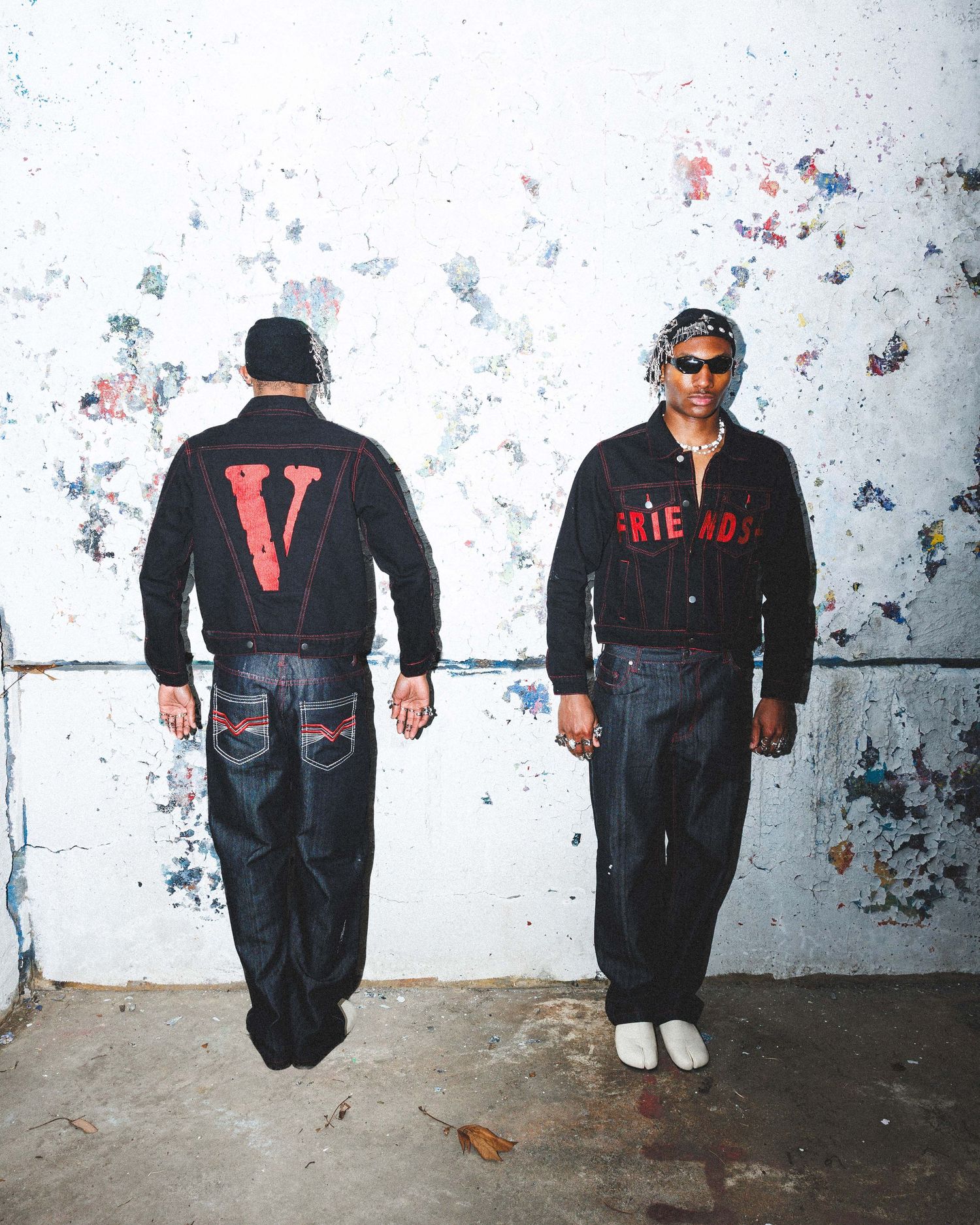 Streetwear editorial campaign featuring two models wearing Vlone apparel against an urban graffiti backdrop, emphasizing contemporary fashio