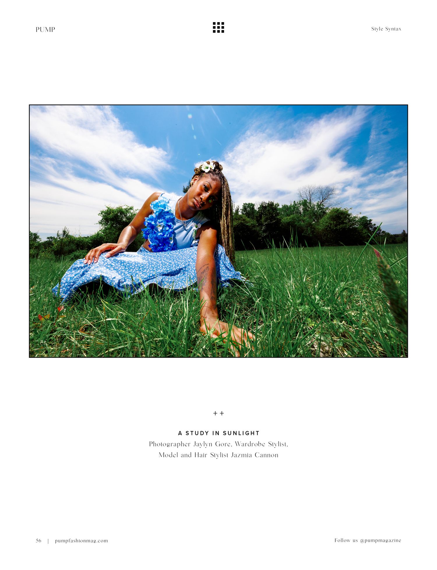 Woman in blue floral dress lying in green grass field under blue sky, editorial fashion shoot titled A Study in Sunlight.