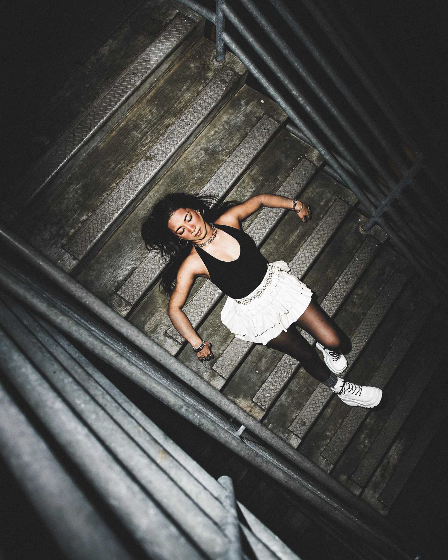 Artistic overhead shots of a person in black clothing lying on wooden floorboards in dim lighting.