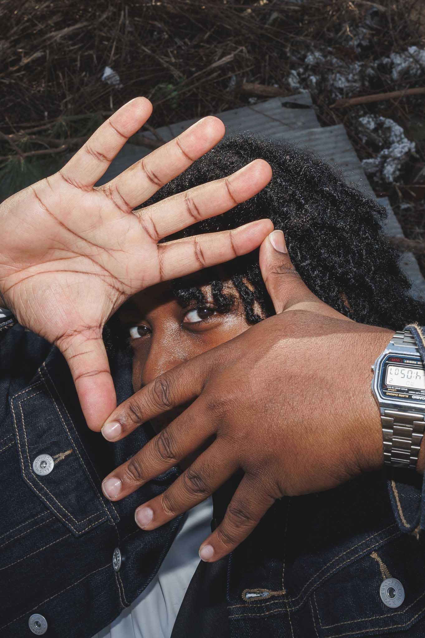 Close-up shots of hands wearing a silver watch against dark denim clothing.
