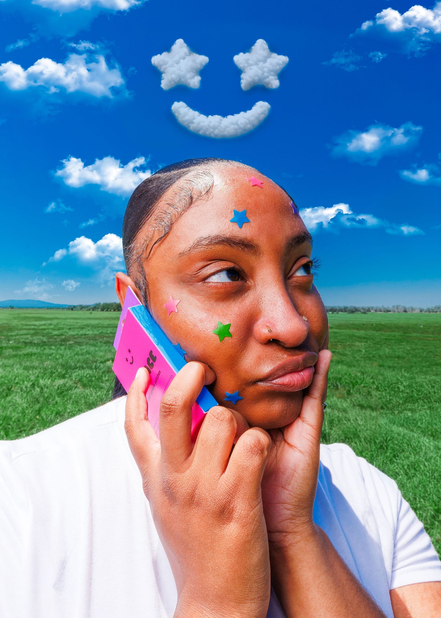 Person with star stickers on face holding pink phone in green field with cloud smiley face in blue sky.