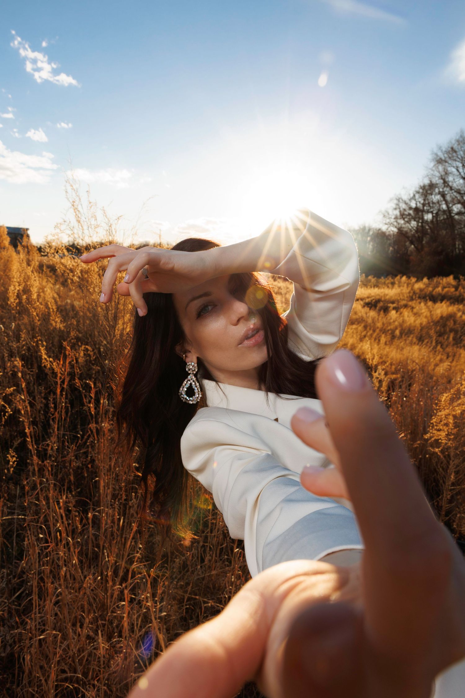 Person in white shirt posing in golden field during sunset.