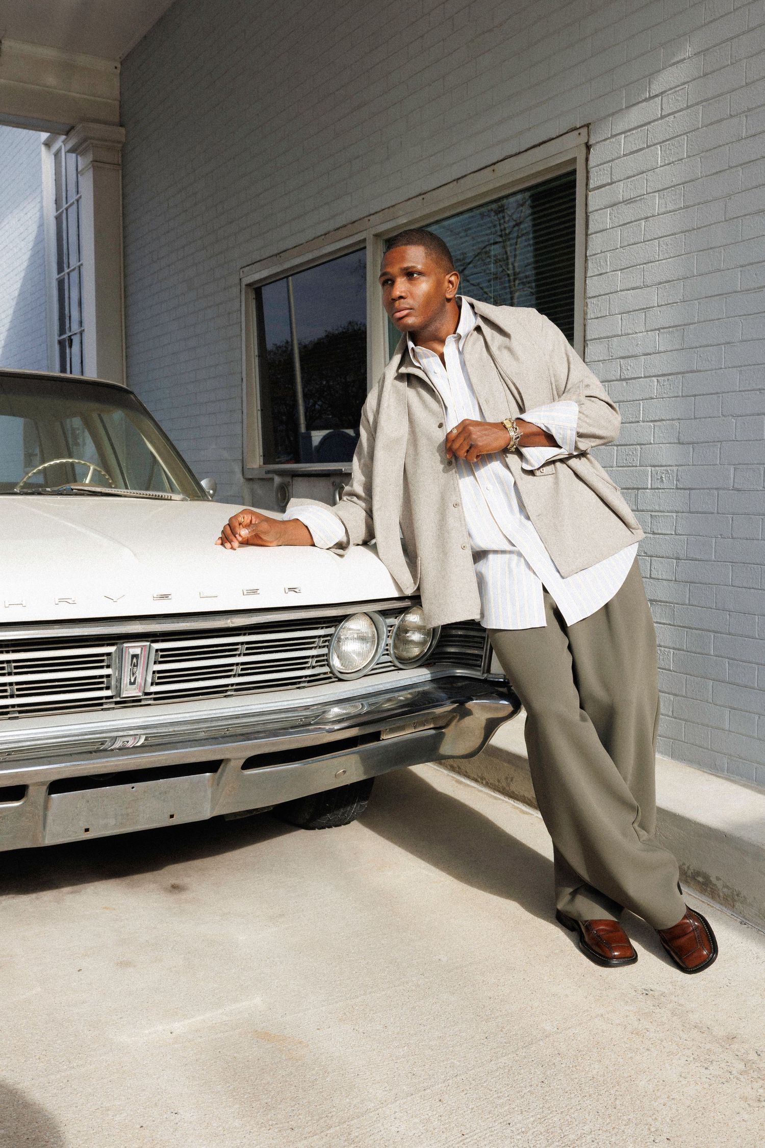 Sequential photos of person in light suit examining vintage car against white brick wall.